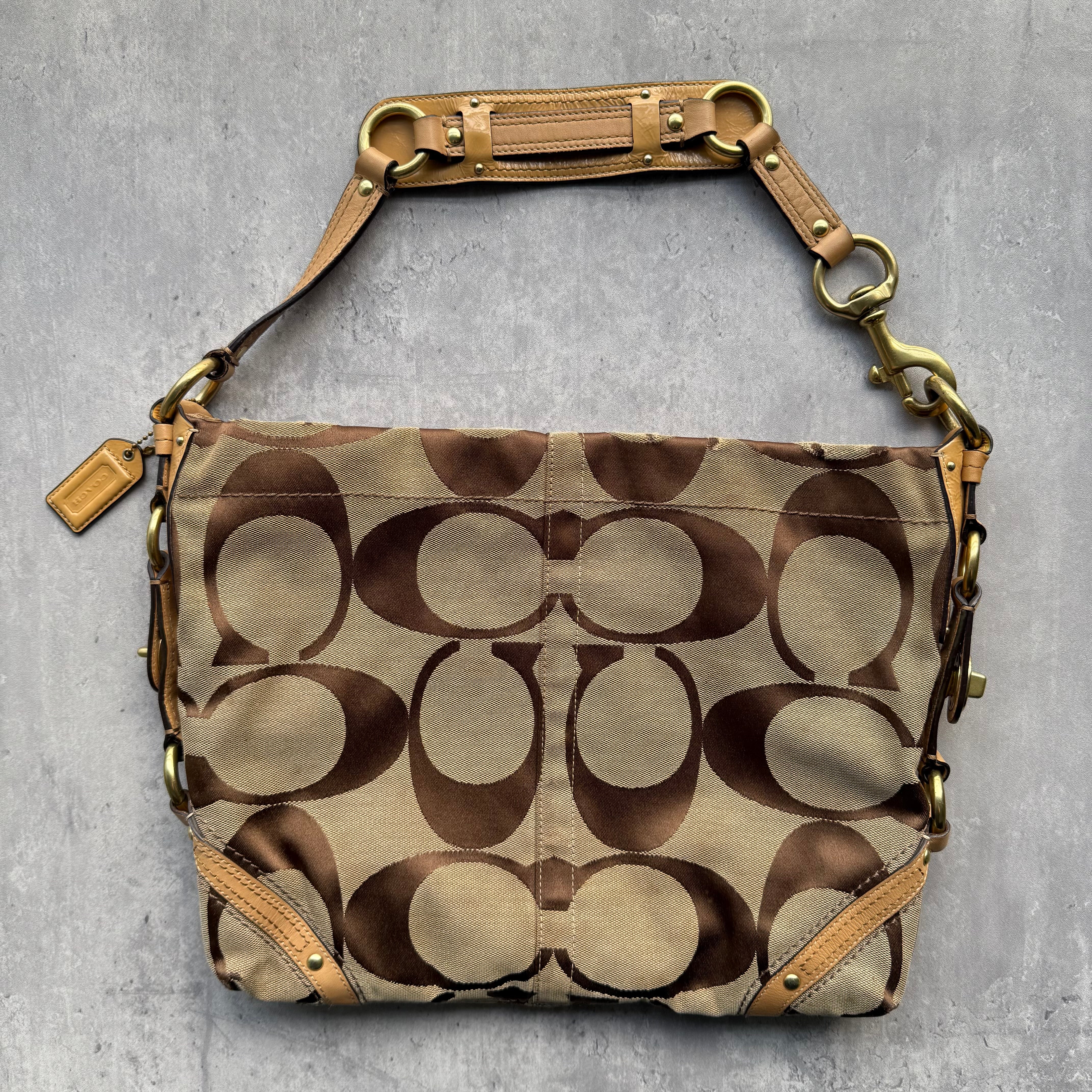 Coach Signature Carly Shoulder Bag in beige monogram canvas with tan leather trim, gold hardware, and purple satin-lined interior