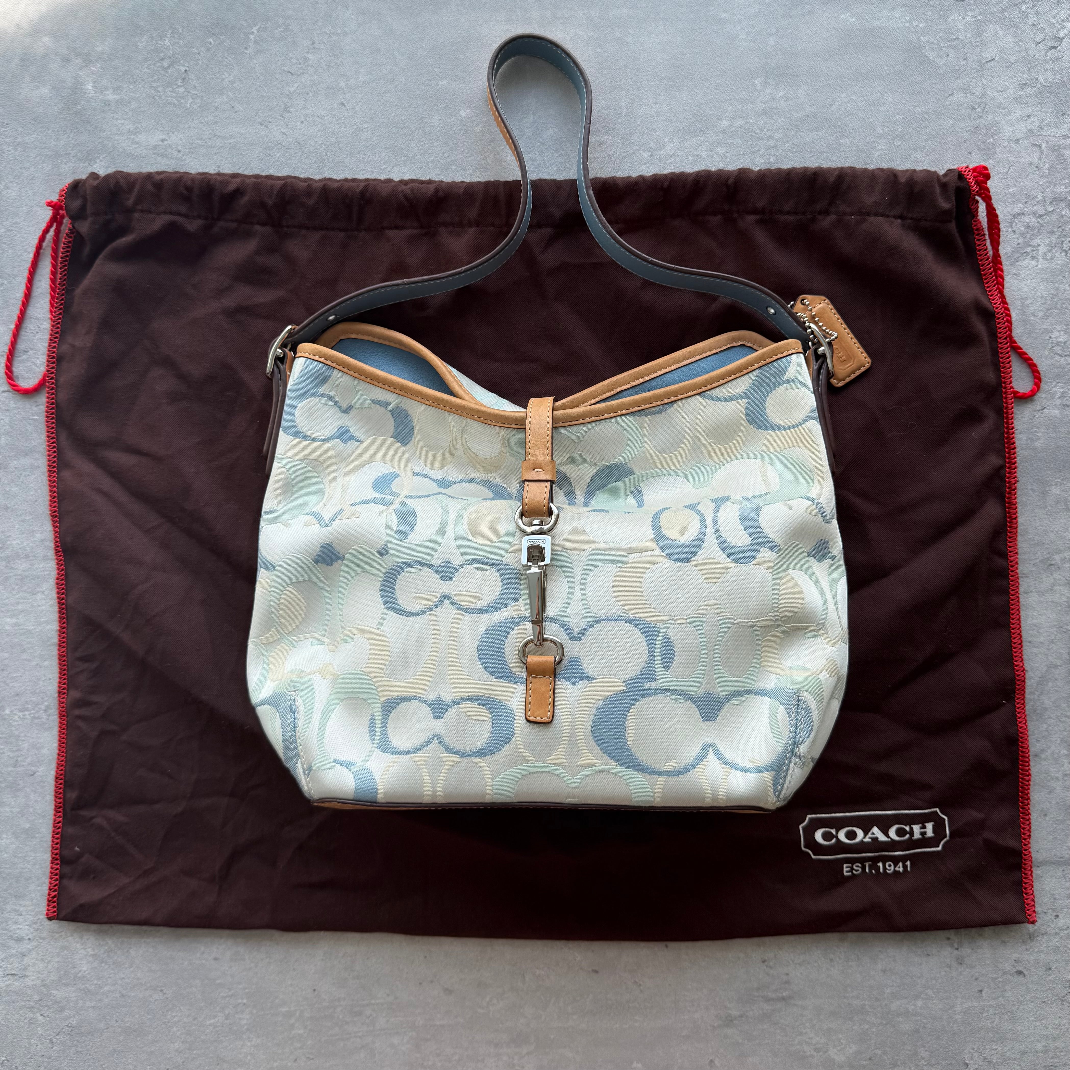 Coach Signature Clip Shoulder Bag in multicolor jacquard with pastel blue, cream, and beige monogram, tan leather trim, and silver-tone clip closure.