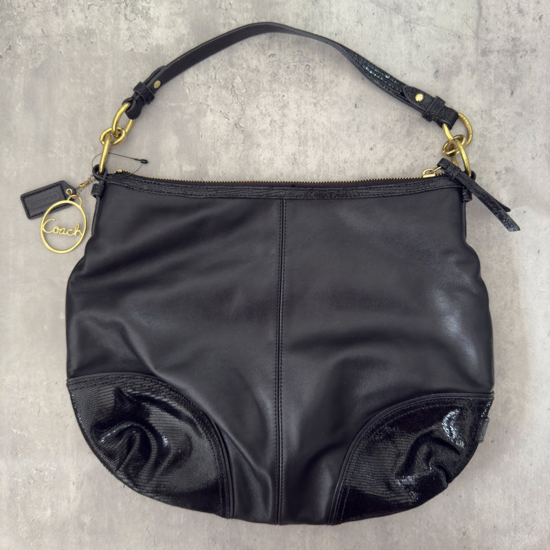 Coach Signature Cursive Logo Shoulder Bag in black leather with gold-tone hardware, featuring a spacious fabric-lined interior and signature Coach charm.