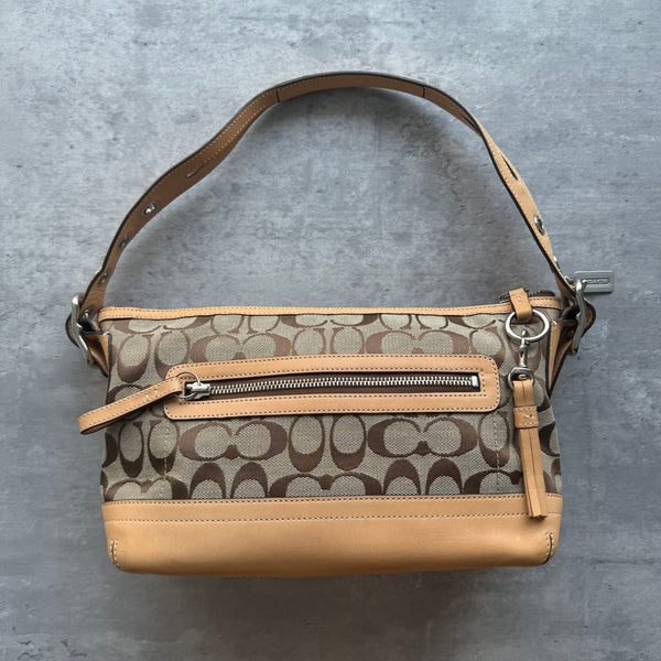 Coach Signature East West Shoulder Bag in beige monogram canvas with tan leather trim, silver hardware, and grommet-detailed strap.
