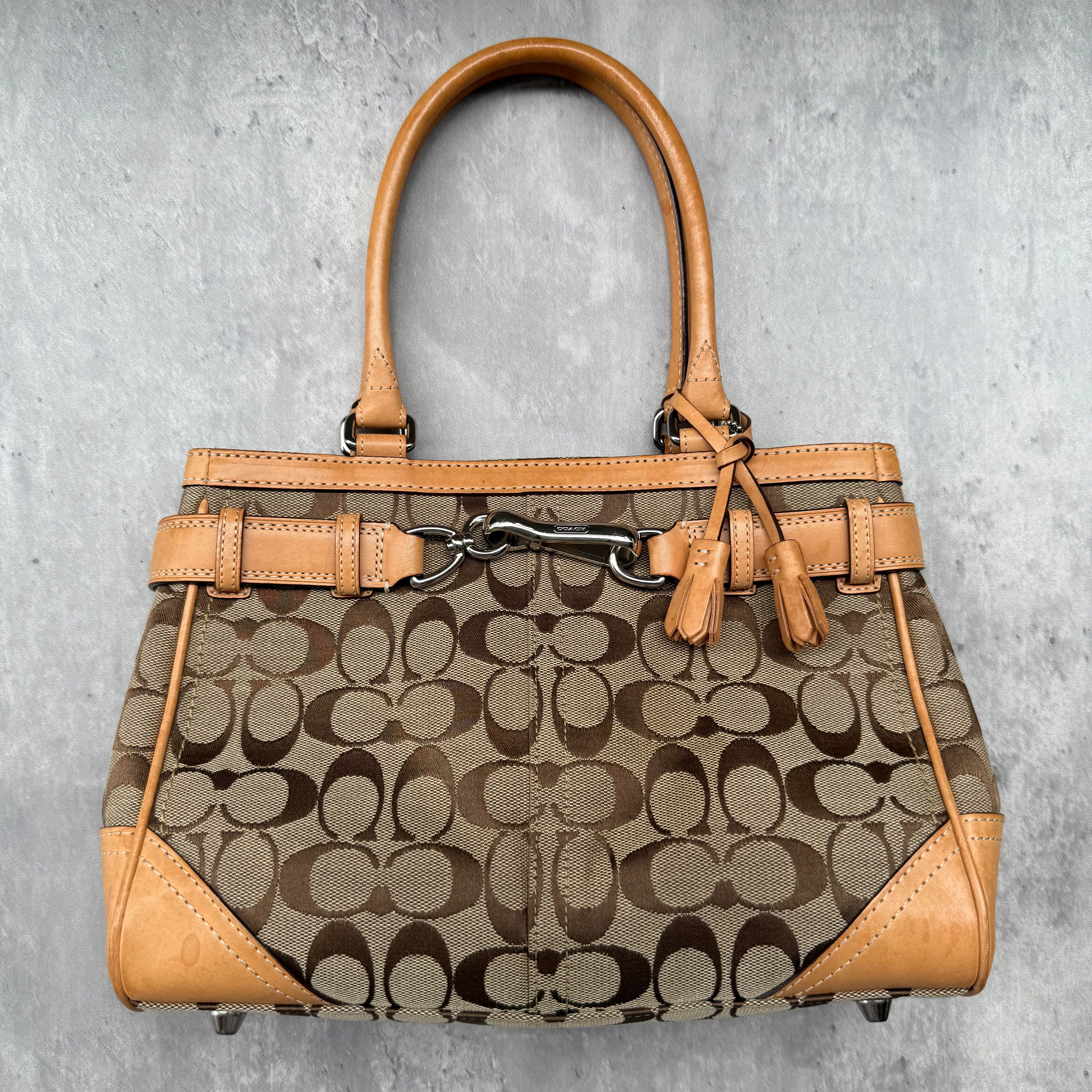 Coach Signature Hampton Satchel Bag in beige and tan canvas with leather trim, silver-tone hardware, and tassel detail.