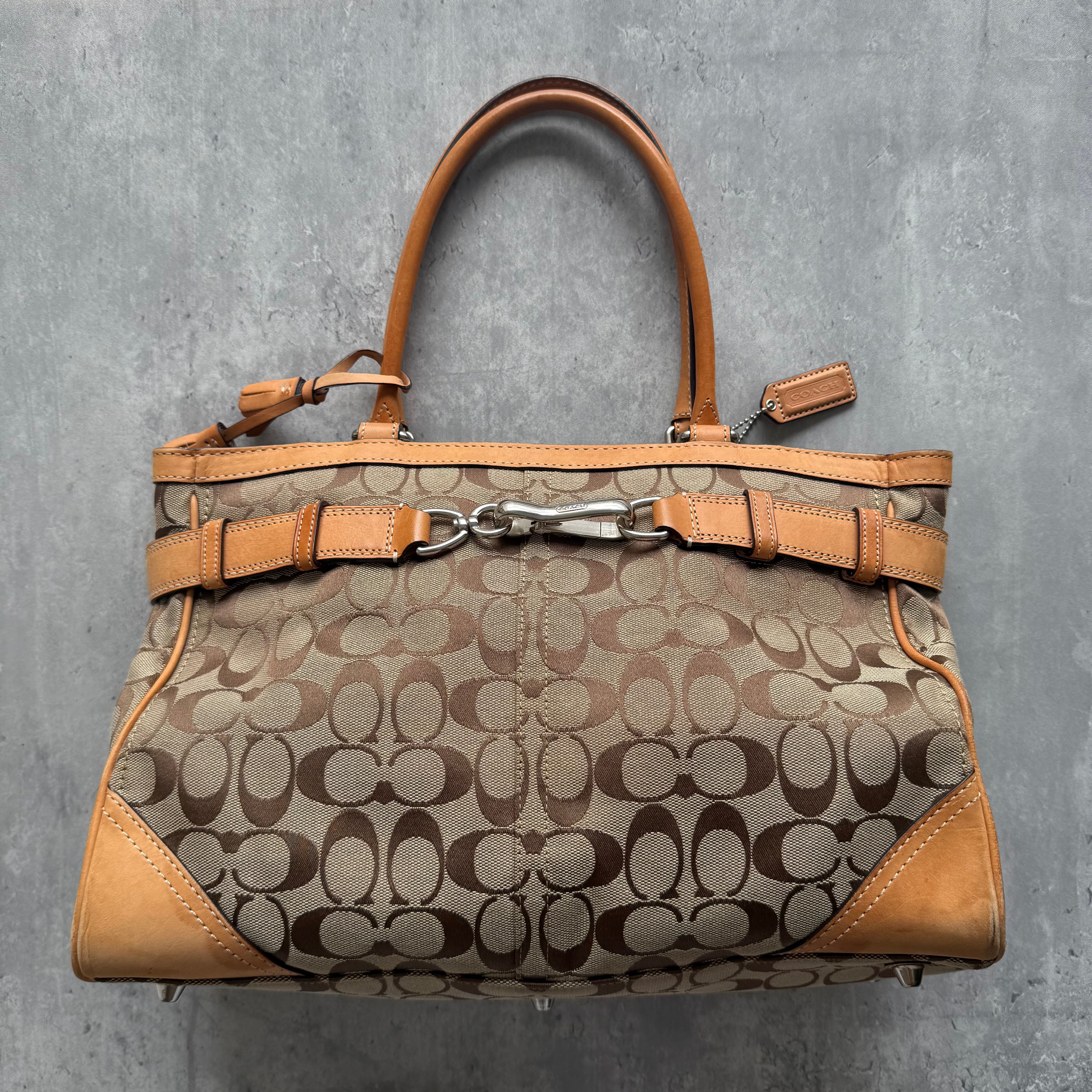 Coach Signature Hamptons Carryall Handbag in tan and beige canvas with leather trim and buckle details.