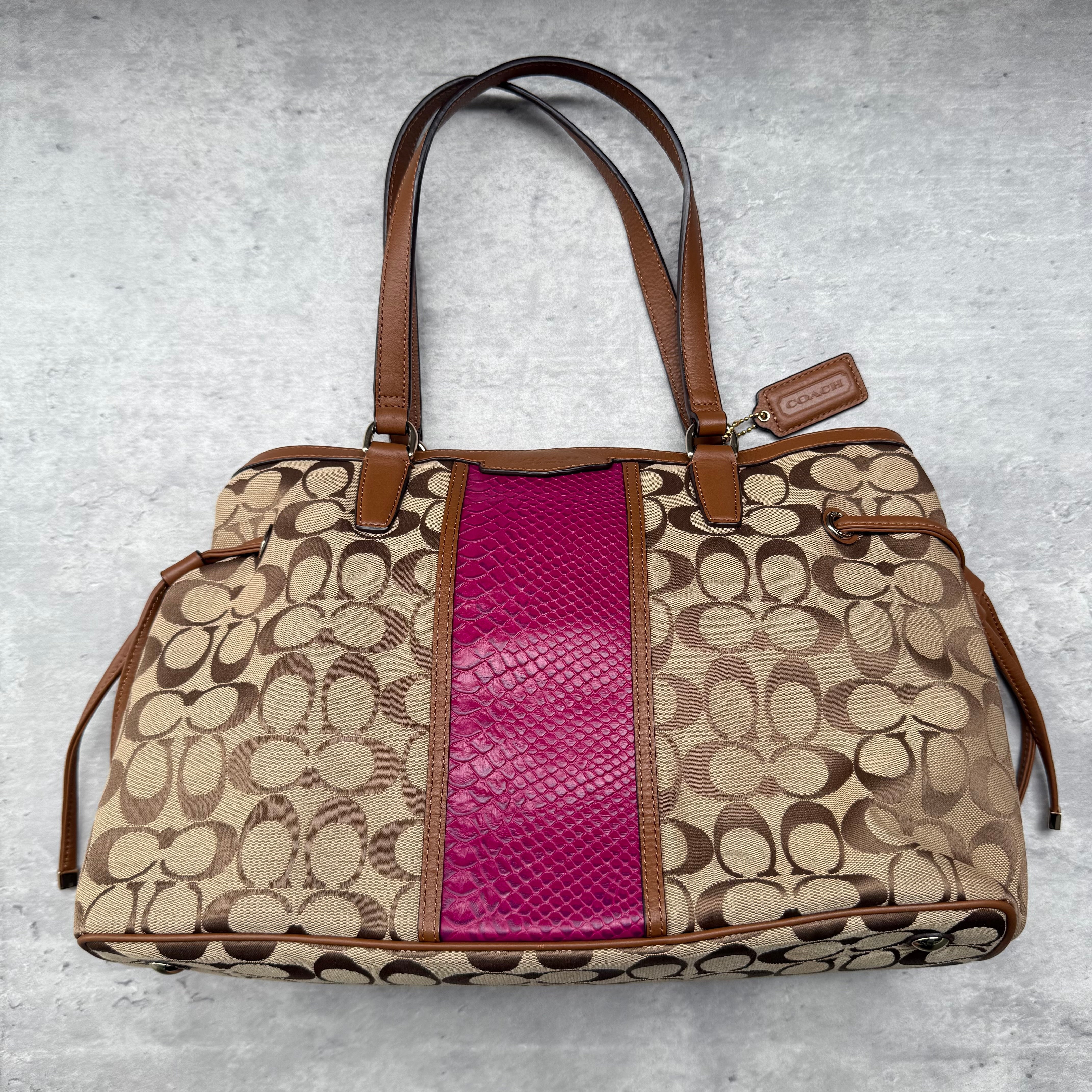 Coach Signature Stripe Drawstring Handbag Beige with pink snakeskin-embossed stripe, featuring dual leather handles and spacious interior.