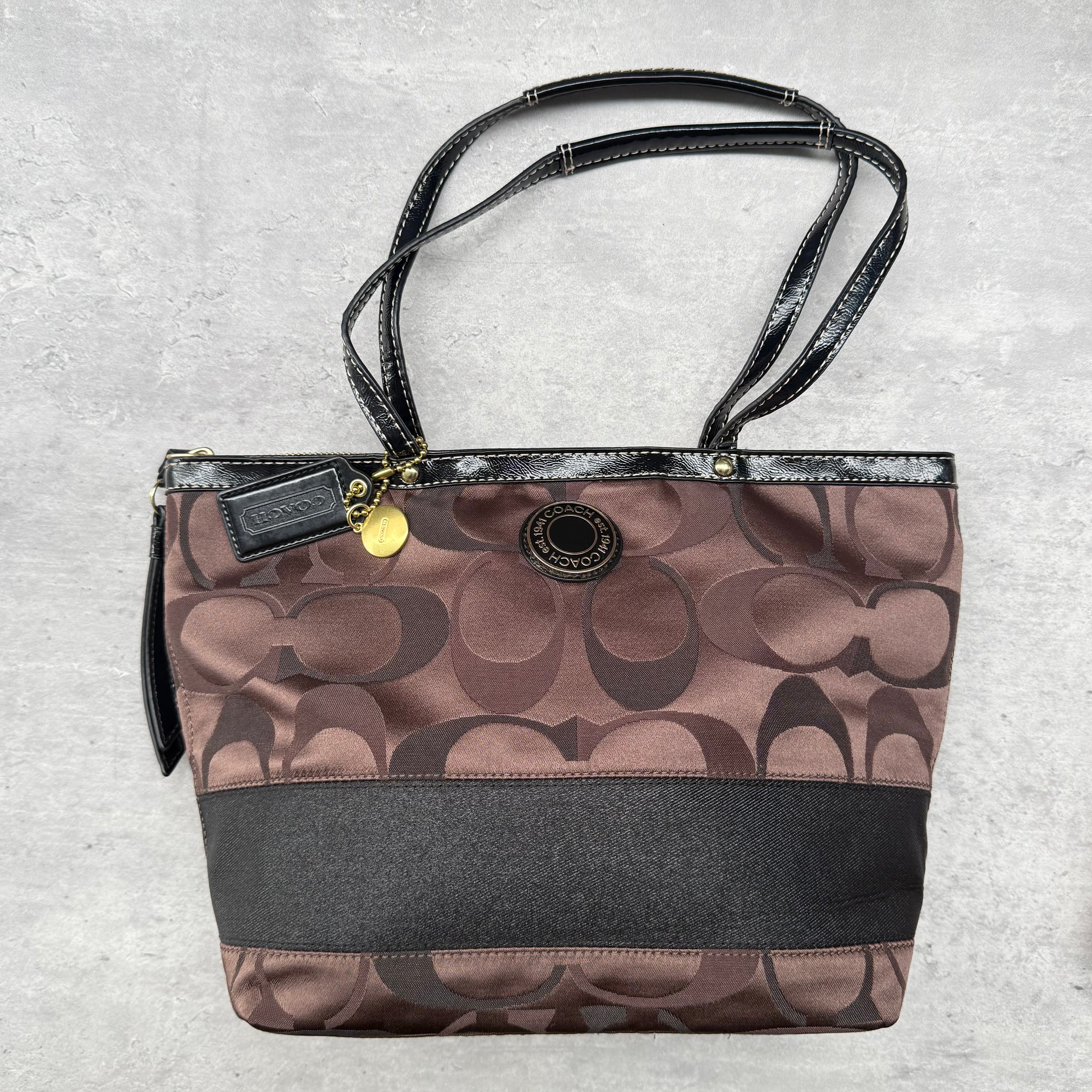 Coach Signature Stripe Tote Bag in brown jacquard with black patent leather trim, gold-tone hardware, and pink interior lining.