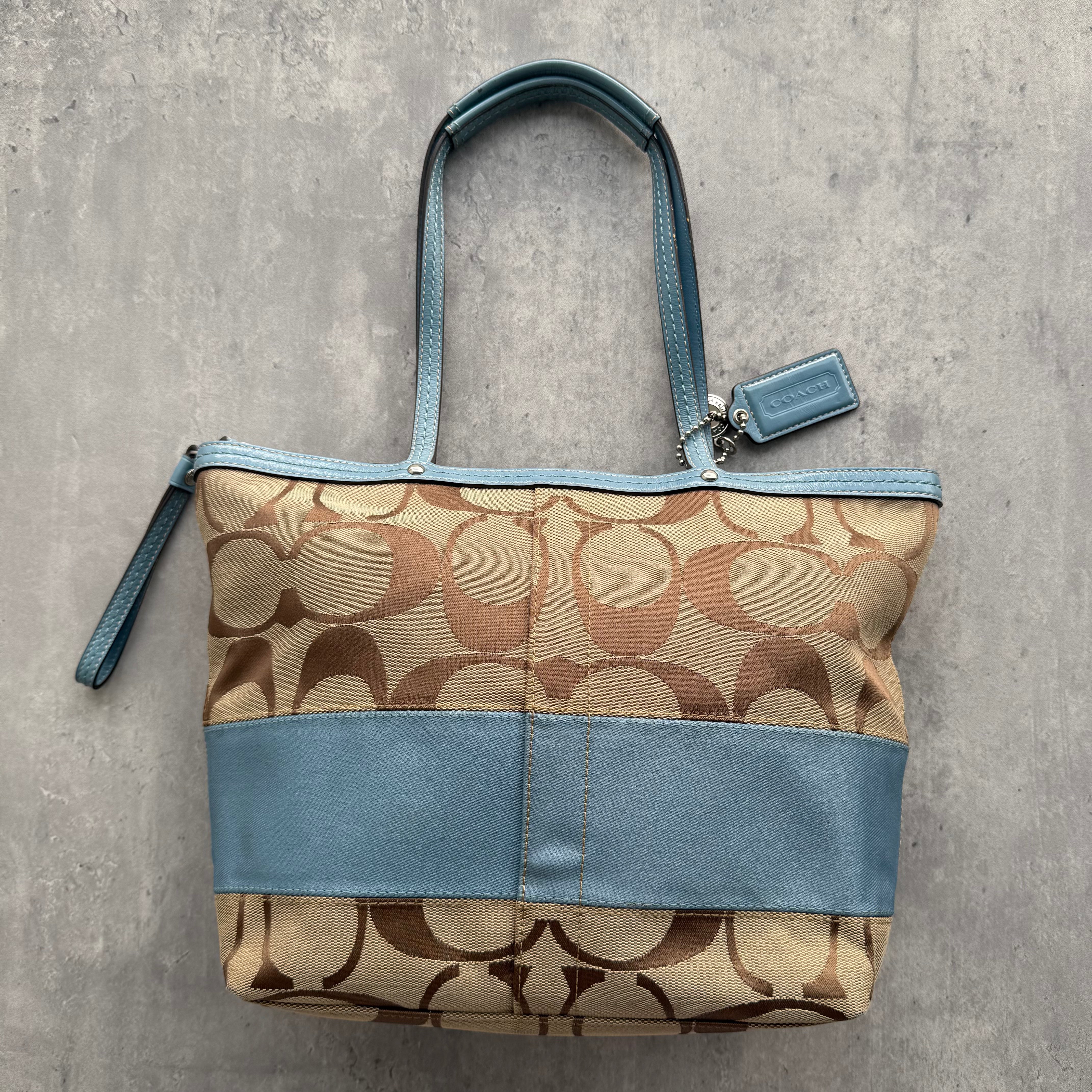 Coach Signature Stripe Tote Bag in beige canvas with light blue leather trim and dual rolled handles.