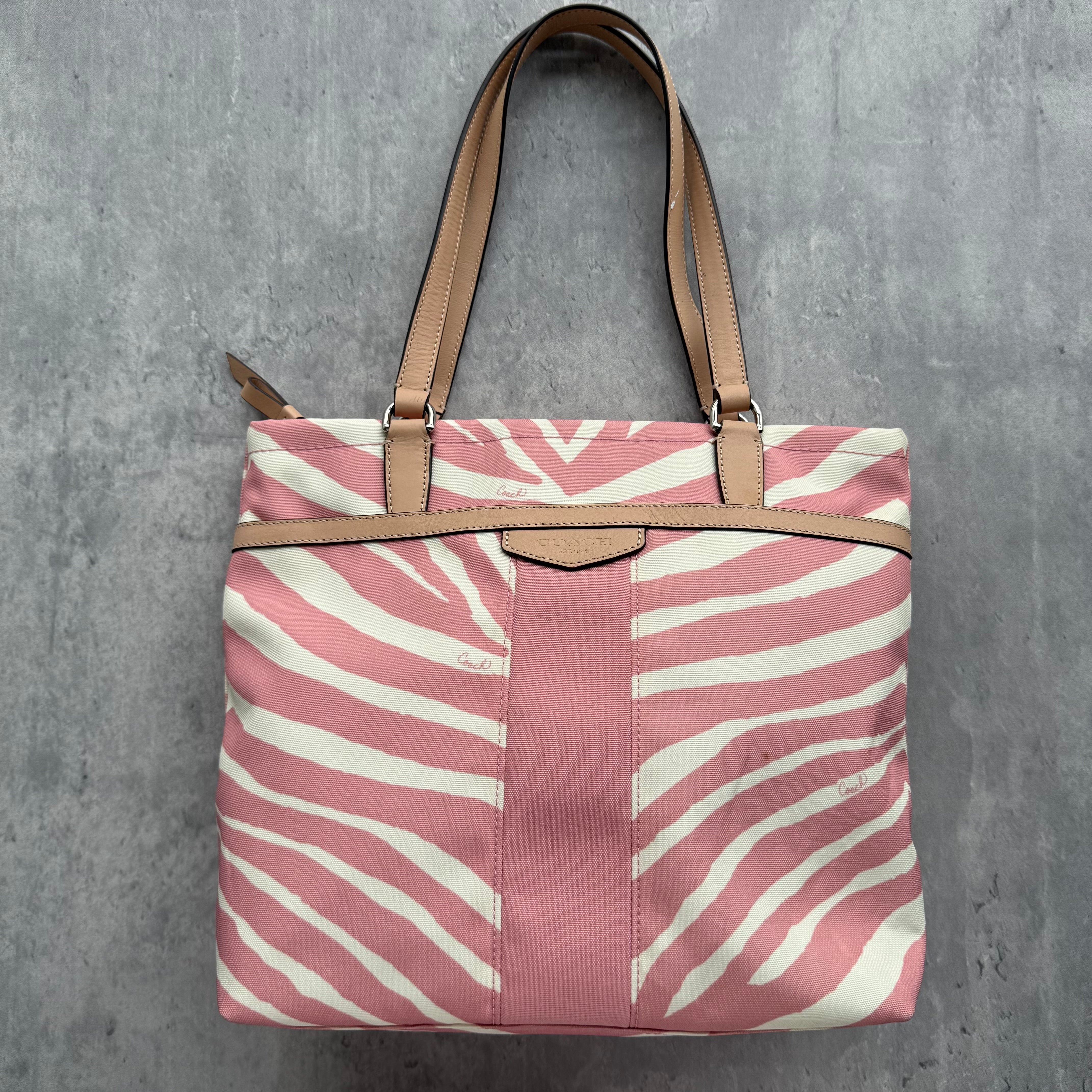 Coach Zebra Striped Carryall Tote Bag Blush Pink/White canvas with tan leather straps, featuring bold zebra print design and spacious interior with zip closure.