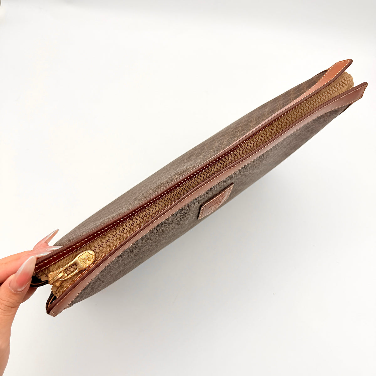 Celine Triomphe Macadam Clutch Bag in brown coated canvas with leather trim, shown against a white background.