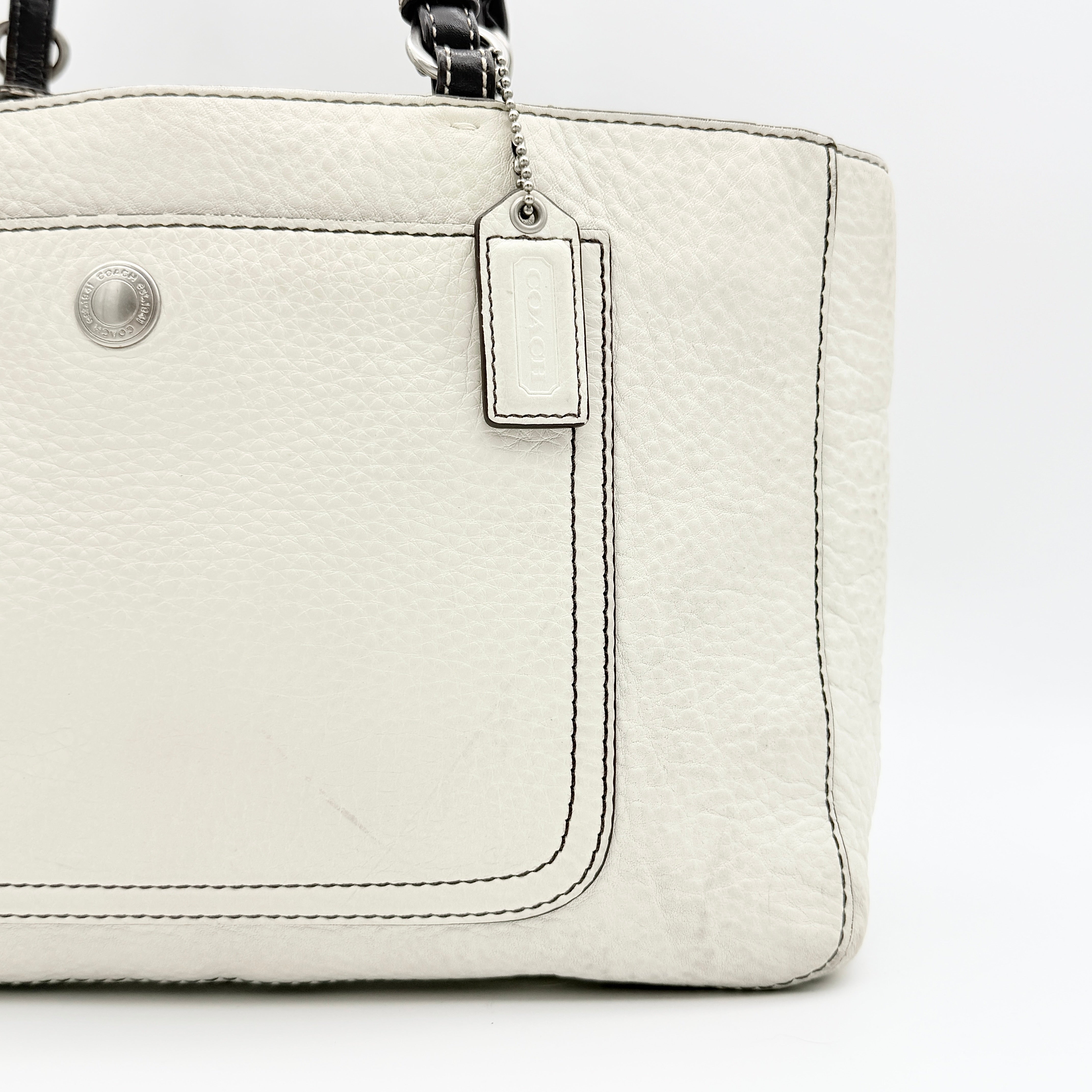 Coach Chelsea Shoulder Bag in ivory leather with black handles and front pocket, photographed against a white background.