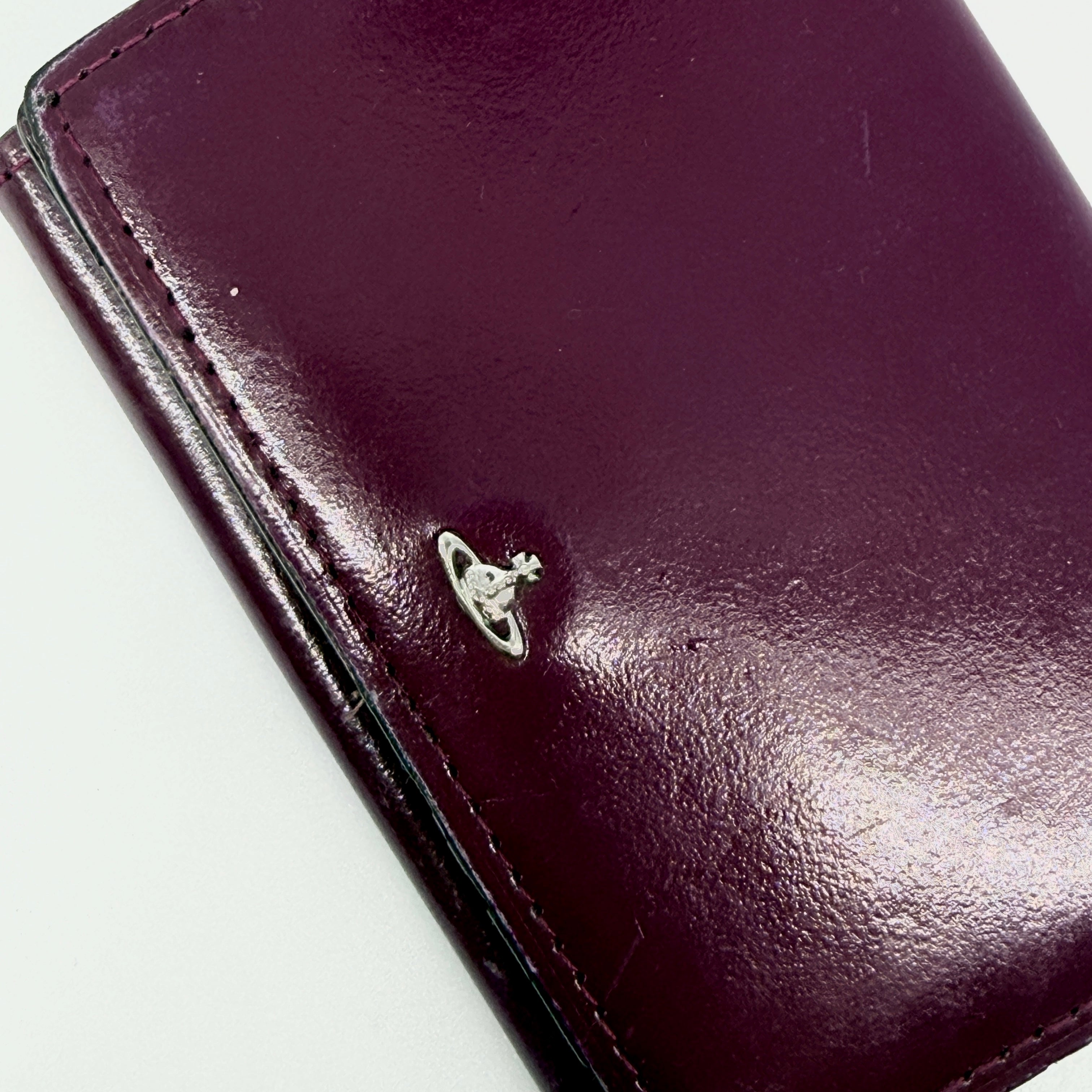 Vivienne Westwood Signature Orb Wallet in glossy purple leather with silver orb emblem on the front flap.