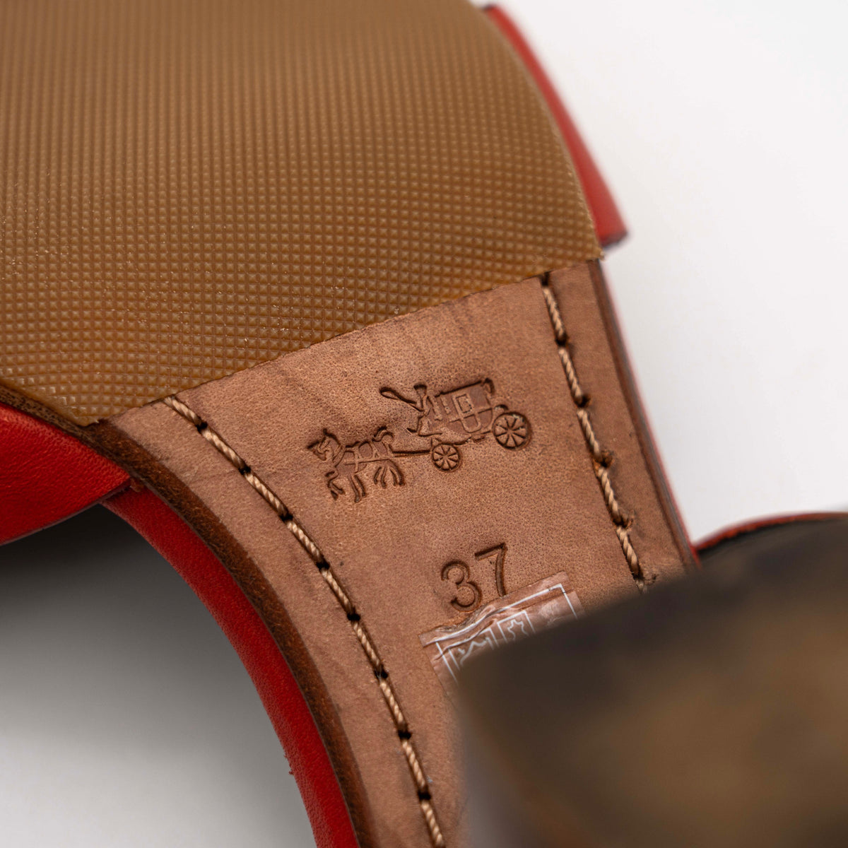 Coach Phoebe block heels in red leather with gold chain detailing, displayed with chunky wood-stacked heels and adjustable ankle straps.