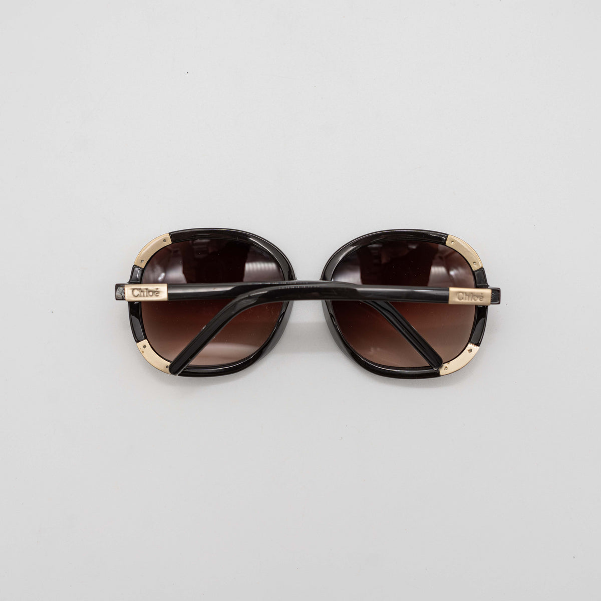 Chloé CL2119 sunglasses in black with gold-tone accents and brown gradient lenses, displayed at an angle.