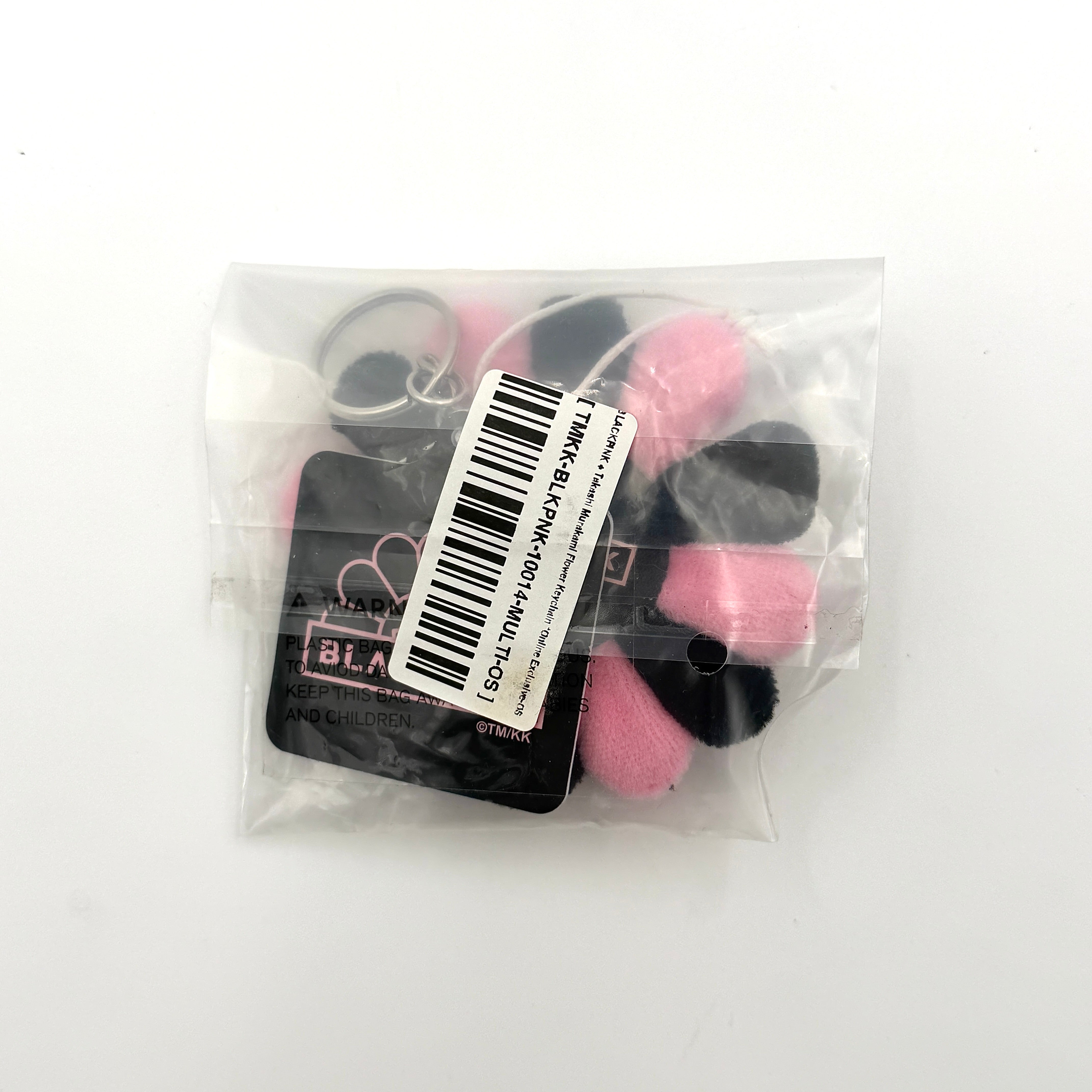 Takashi Murakami x BLACKPINK plush flower keychain in black and pink with smiling face and branded tag.