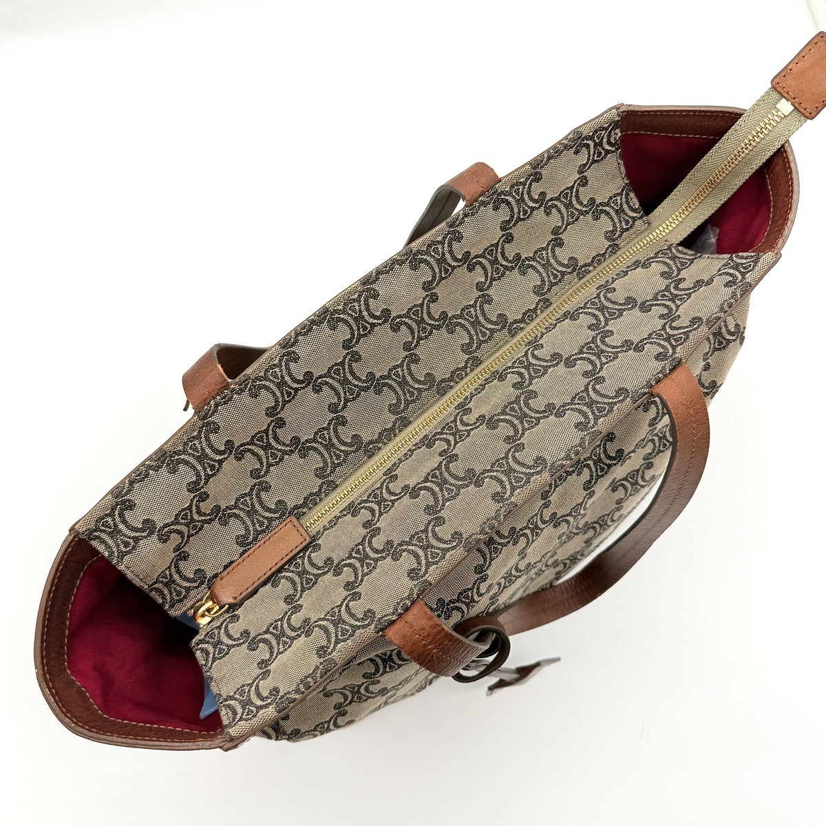 Celine Triomphe Macadam Canvas Tote Bag in beige and brown with leather trim and top handles, styled against a white background.