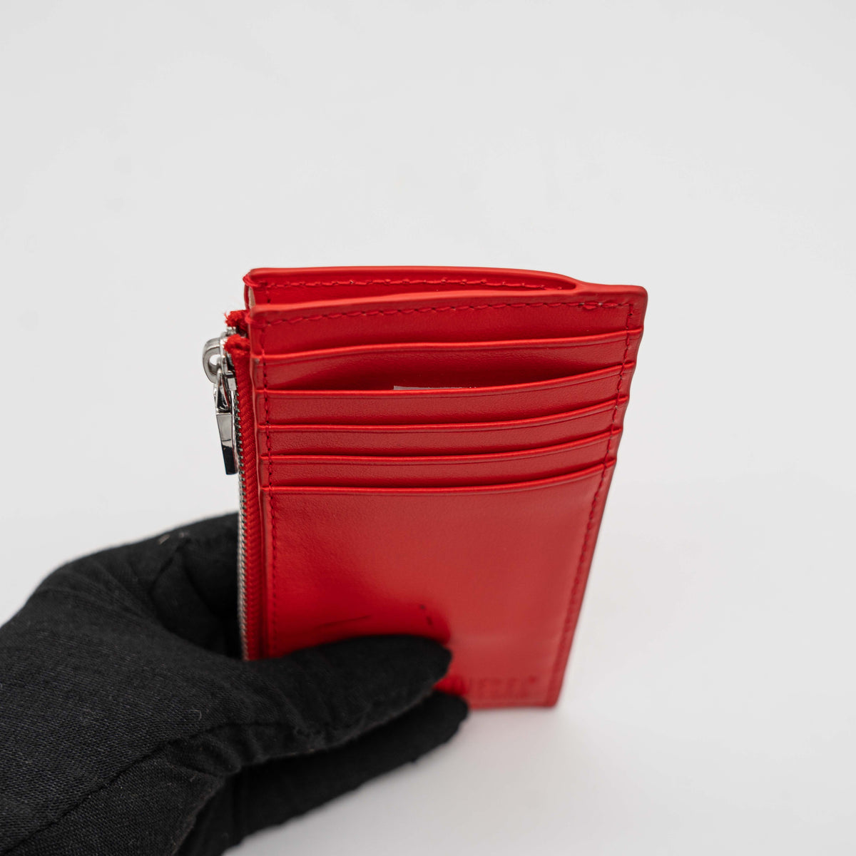 Diesel red patent card holder with silver logo plaque and top zip, set against a clean background.