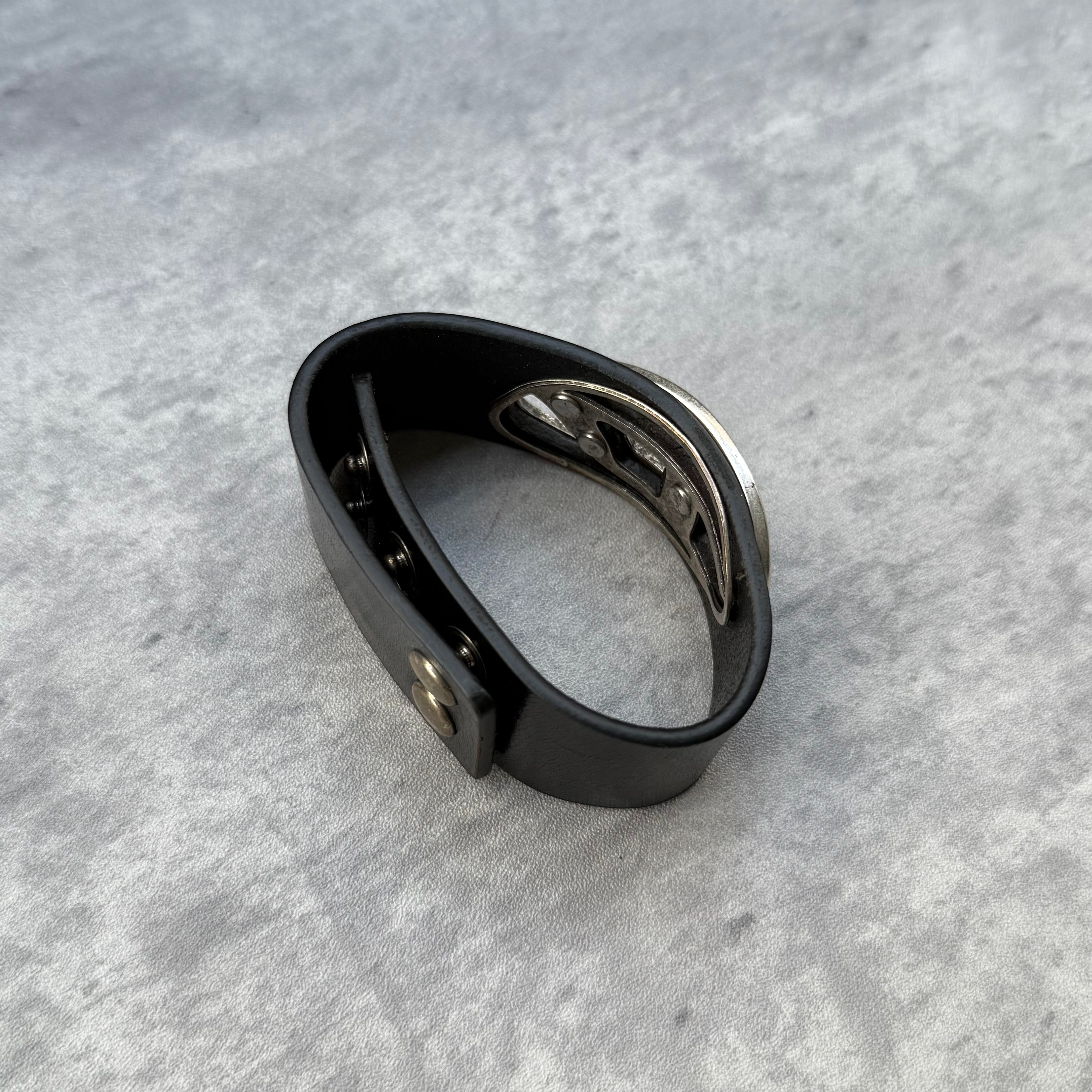 Pre-loved Diesel A-Balone bracelet in black resin with silver cut-out logo, slip-on cuff style, displayed with red drawstring pouch