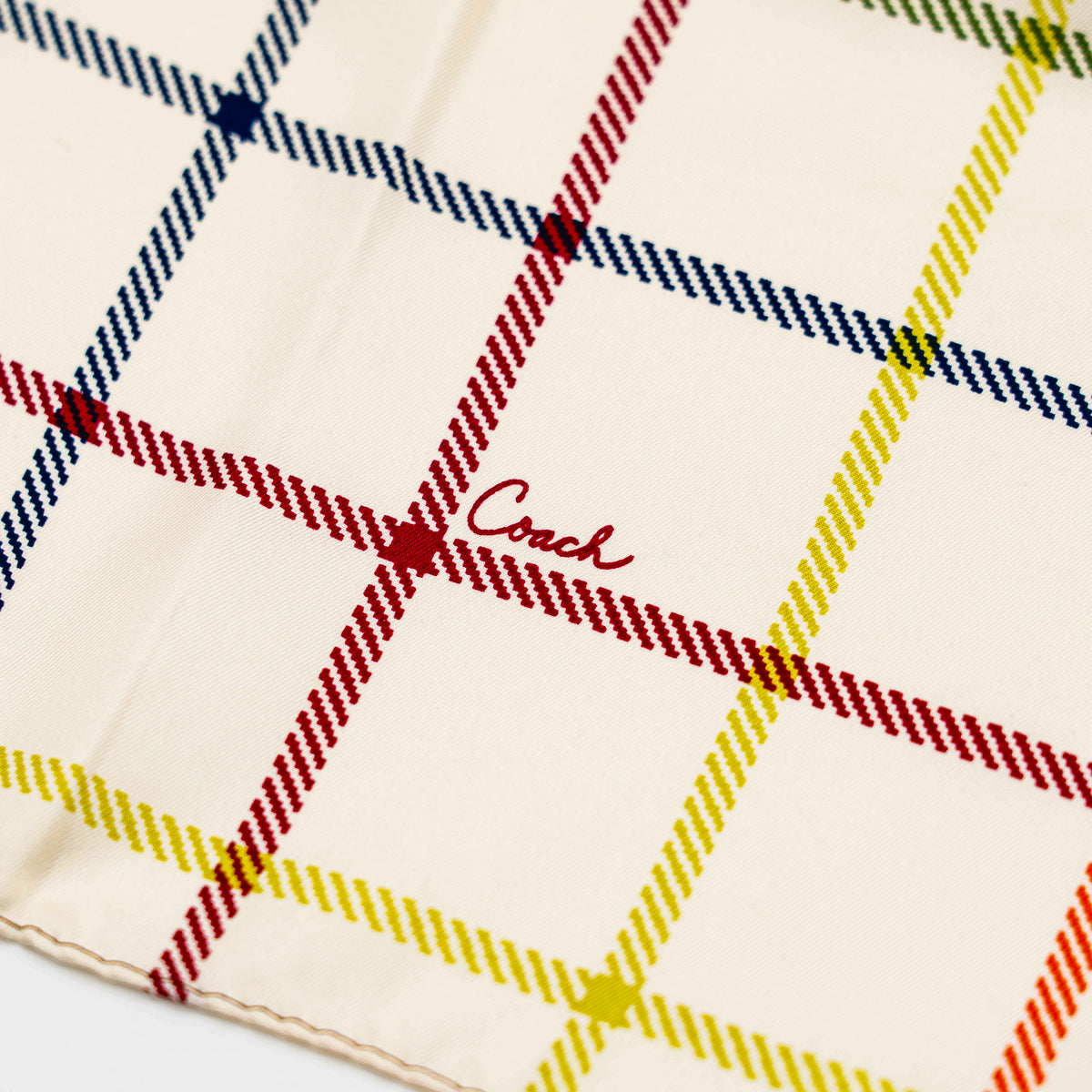 Coach patchwork silk scarf featuring multicolour monogram and checked panels, shown laid flat.