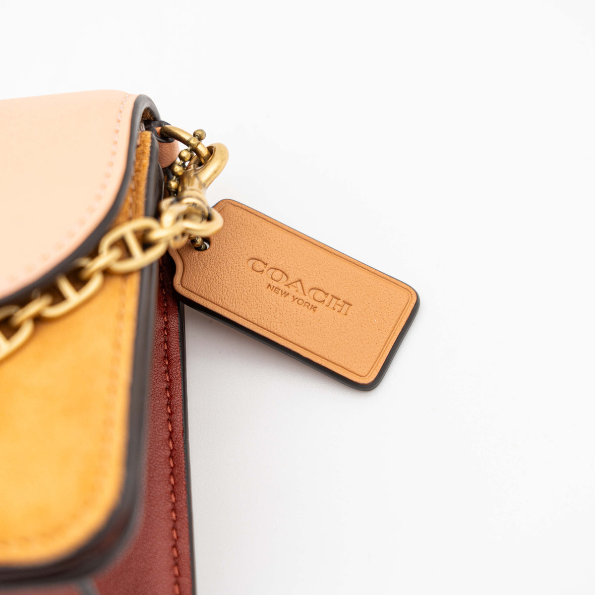 Coach Beat Crossbody Clutch 2Way in blush, tan, and red leather with brass hardware and detachable strap, displayed with chain handle.