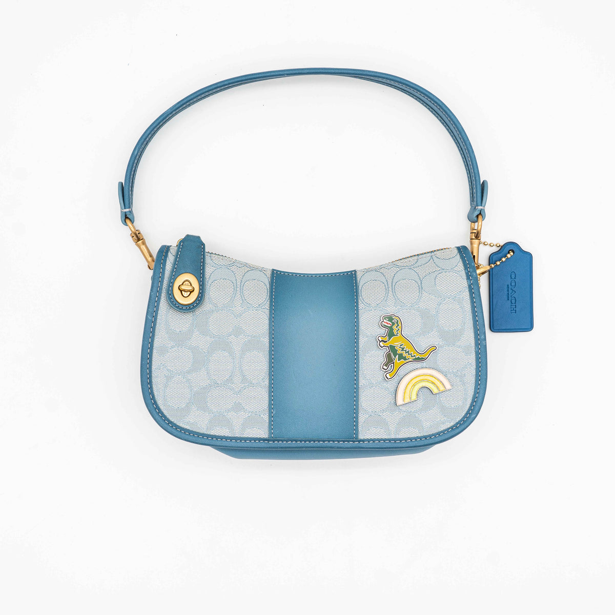 Coach 2Way Signature Swinger Shoulder Bag in light blue monogram canvas and leather with dinosaur and rainbow patches, shown with detachable strap.