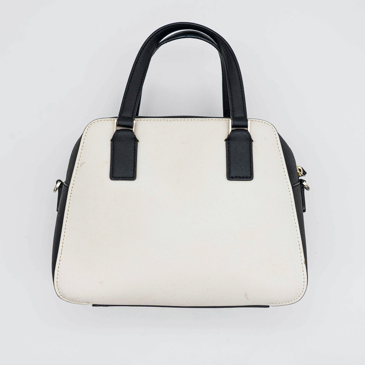 Kate Spade Cameron Street Little Babe satchel in black and white leather with gold hardware, shown with dual handles against a minimal background.