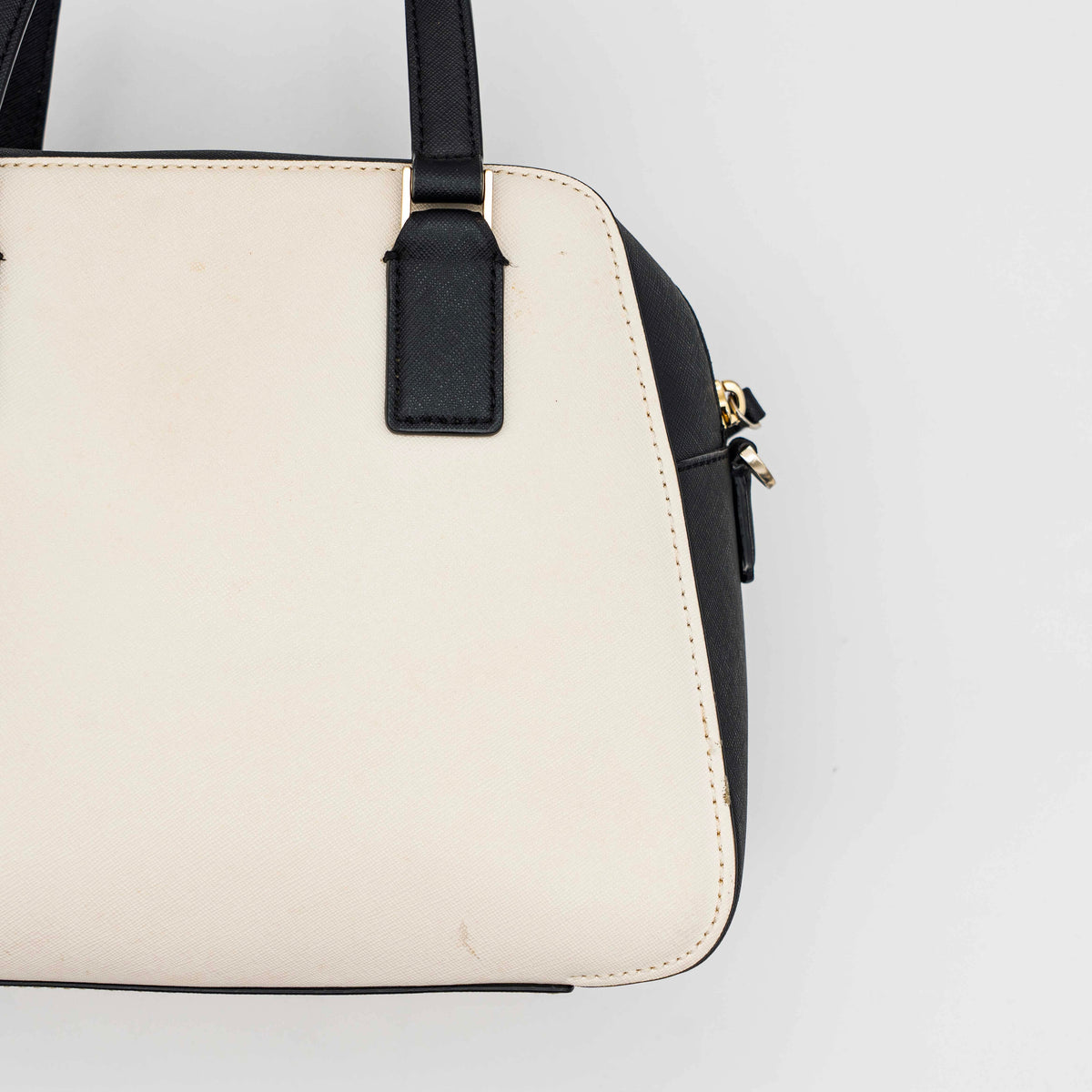 Kate Spade Cameron Street Little Babe satchel in black and white leather with gold hardware, shown with dual handles against a minimal background.