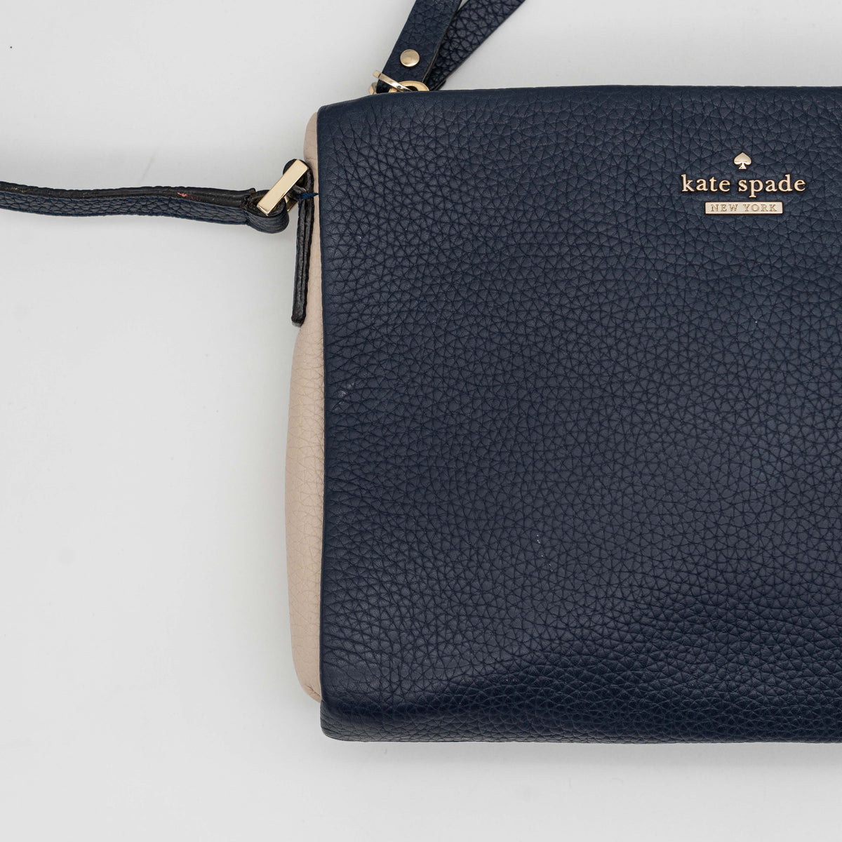 Kate Spade navy blue crossbody bag in pebbled leather, shown with adjustable strap and gold-tone accents.