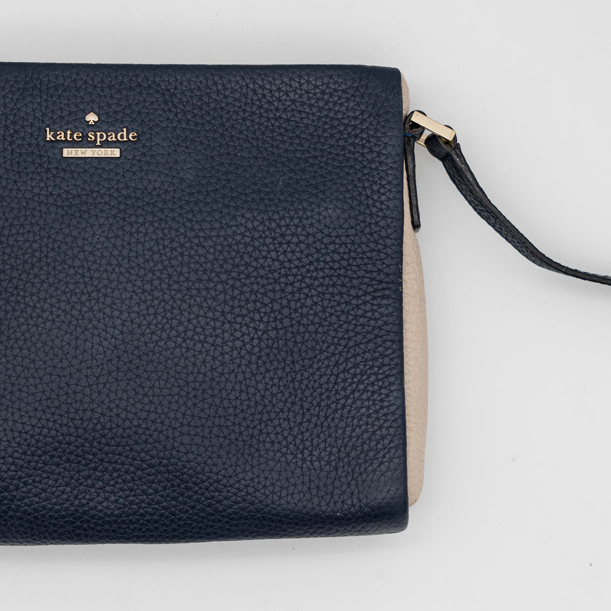 Kate Spade navy blue crossbody bag in pebbled leather, shown with adjustable strap and gold-tone accents.