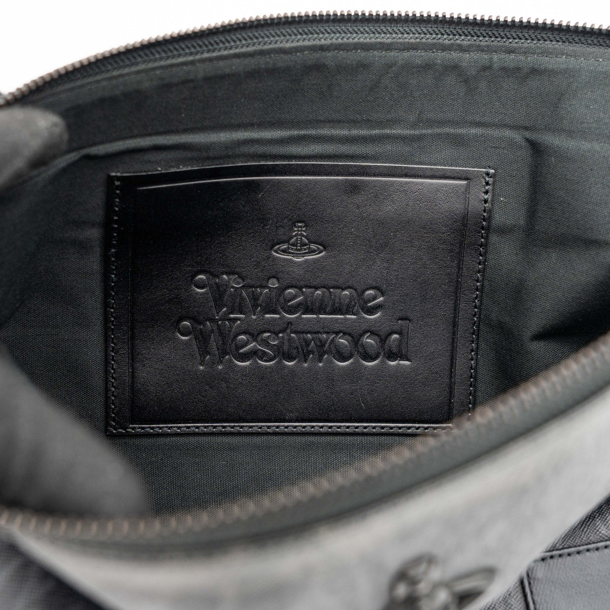 Vivienne Westwood clutch bag in grey and black graphic camouflage with matte black Orb logo and leather trim, styled against a white background.