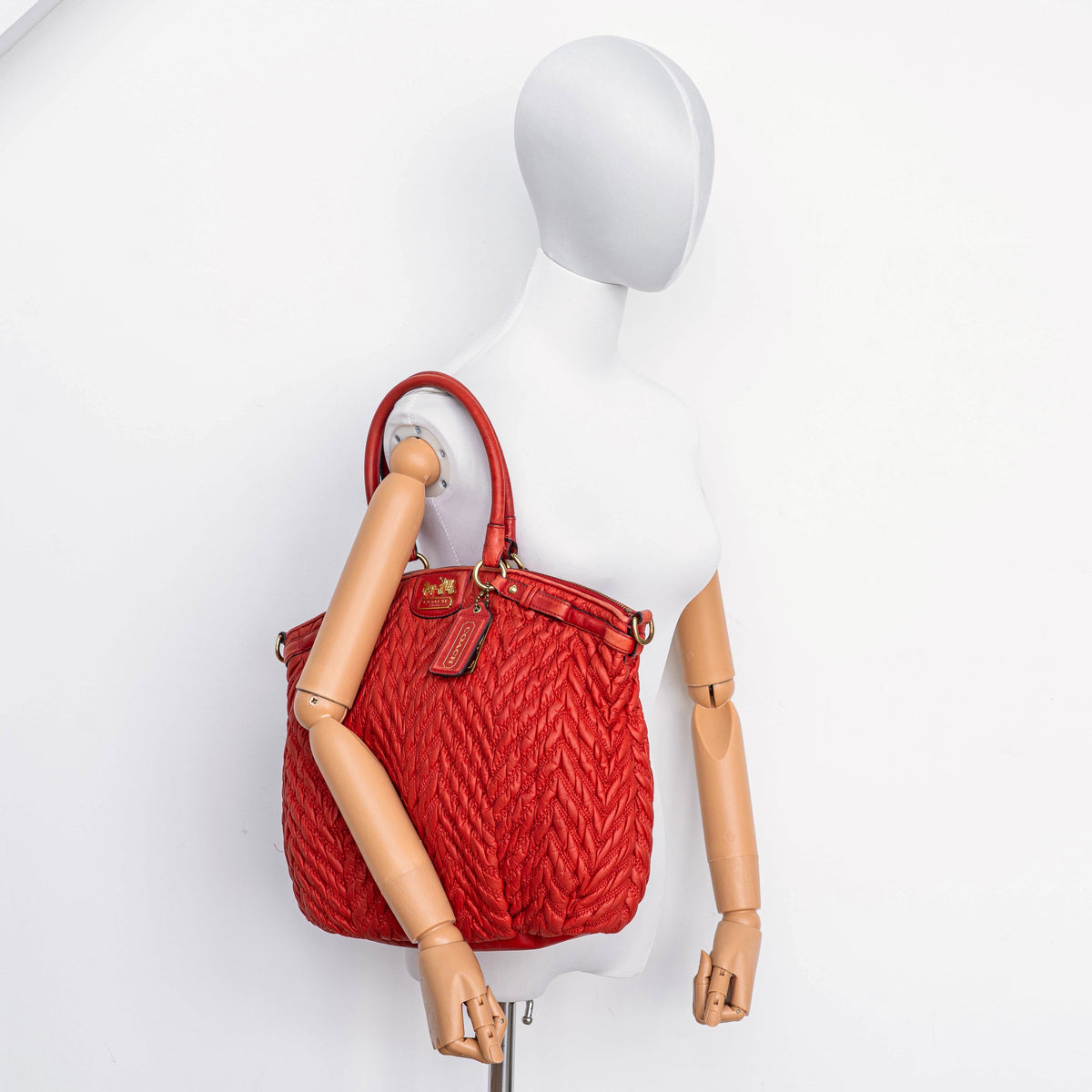 Coach Madison 2Way shoulder bag in rich red quilted texture with gold hardware, top handles, and detachable strap, displayed on a white background.
