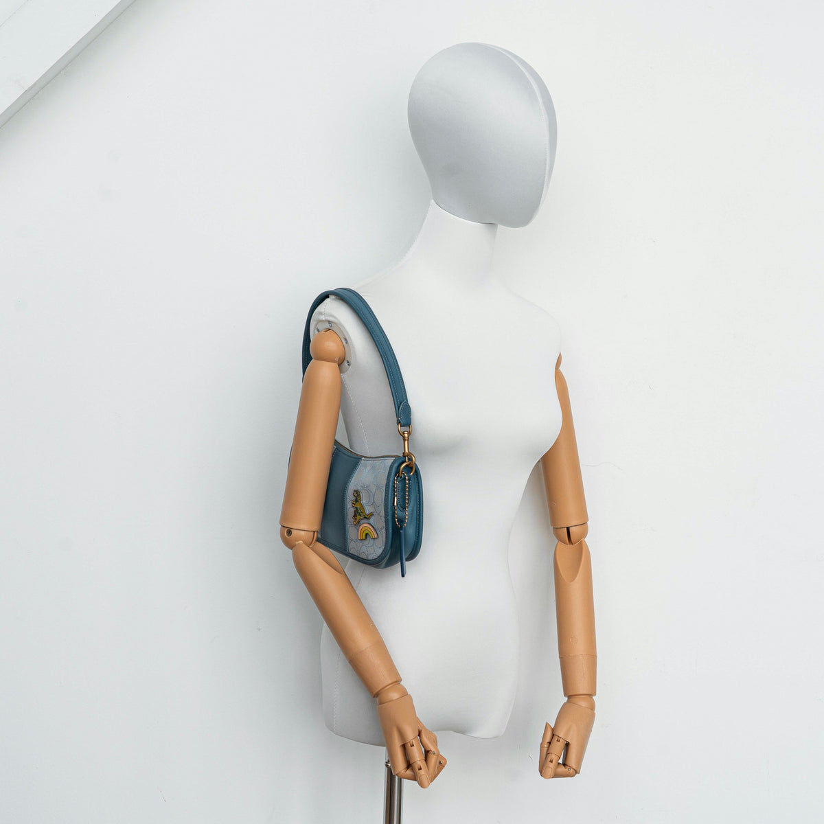 Coach 2Way Signature Swinger Shoulder Bag in light blue monogram canvas and leather with dinosaur and rainbow patches, shown with detachable strap.