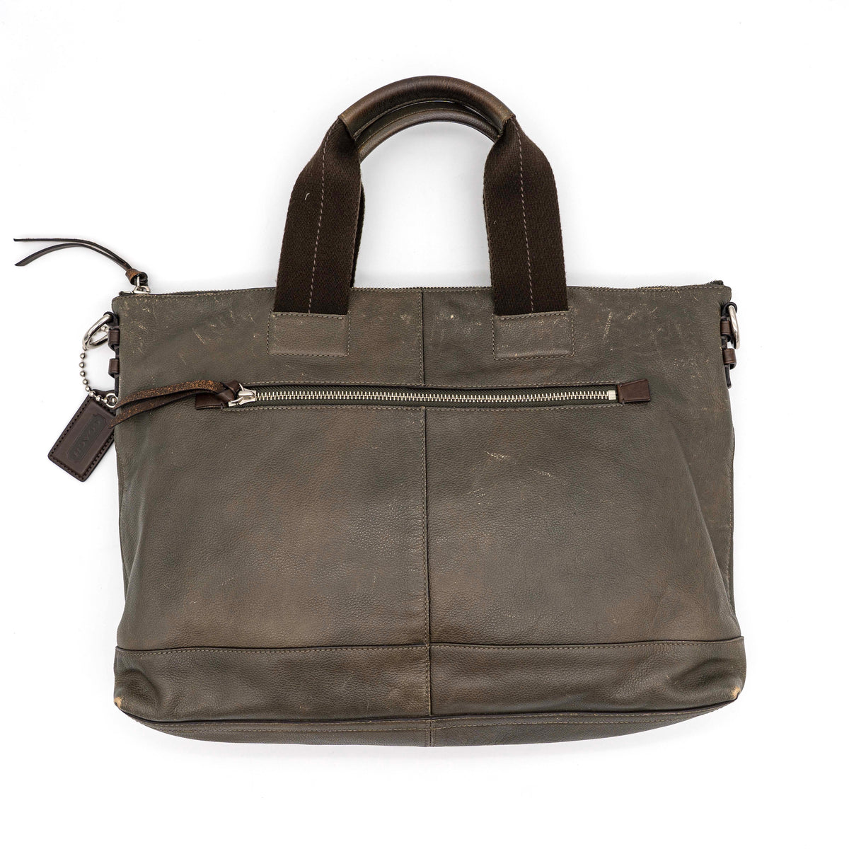 Coach brown leather tote bag with double handles and front zip pocket, shown on a white background.
