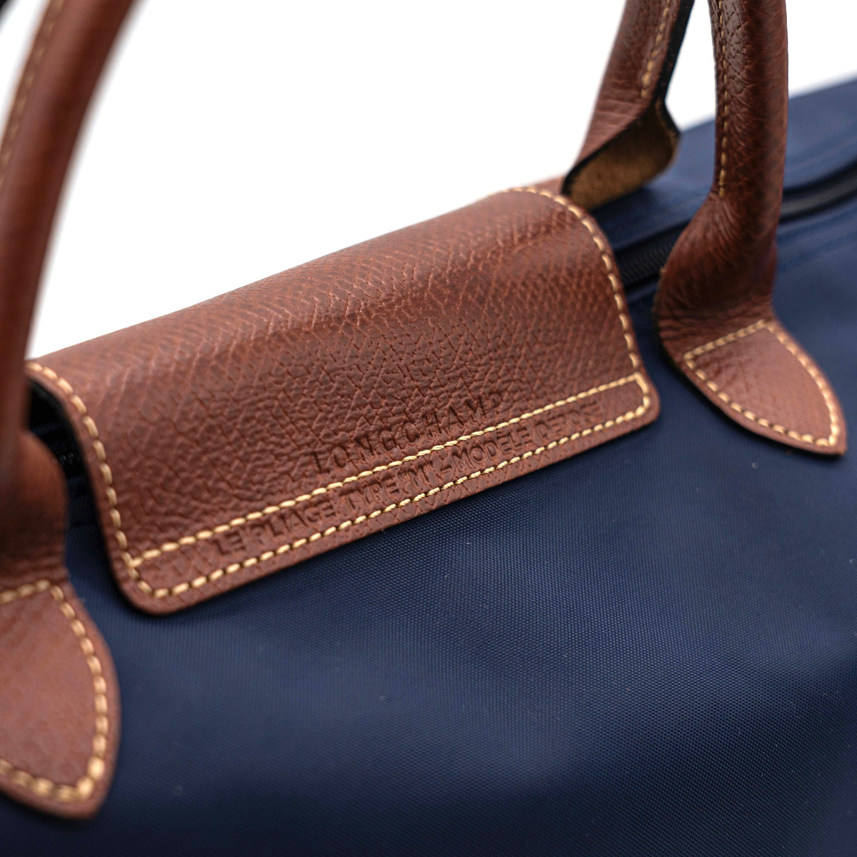 Longchamp Le Pliage Original handbag in navy blue nylon with brown leather handles and trim, shown against a white background.