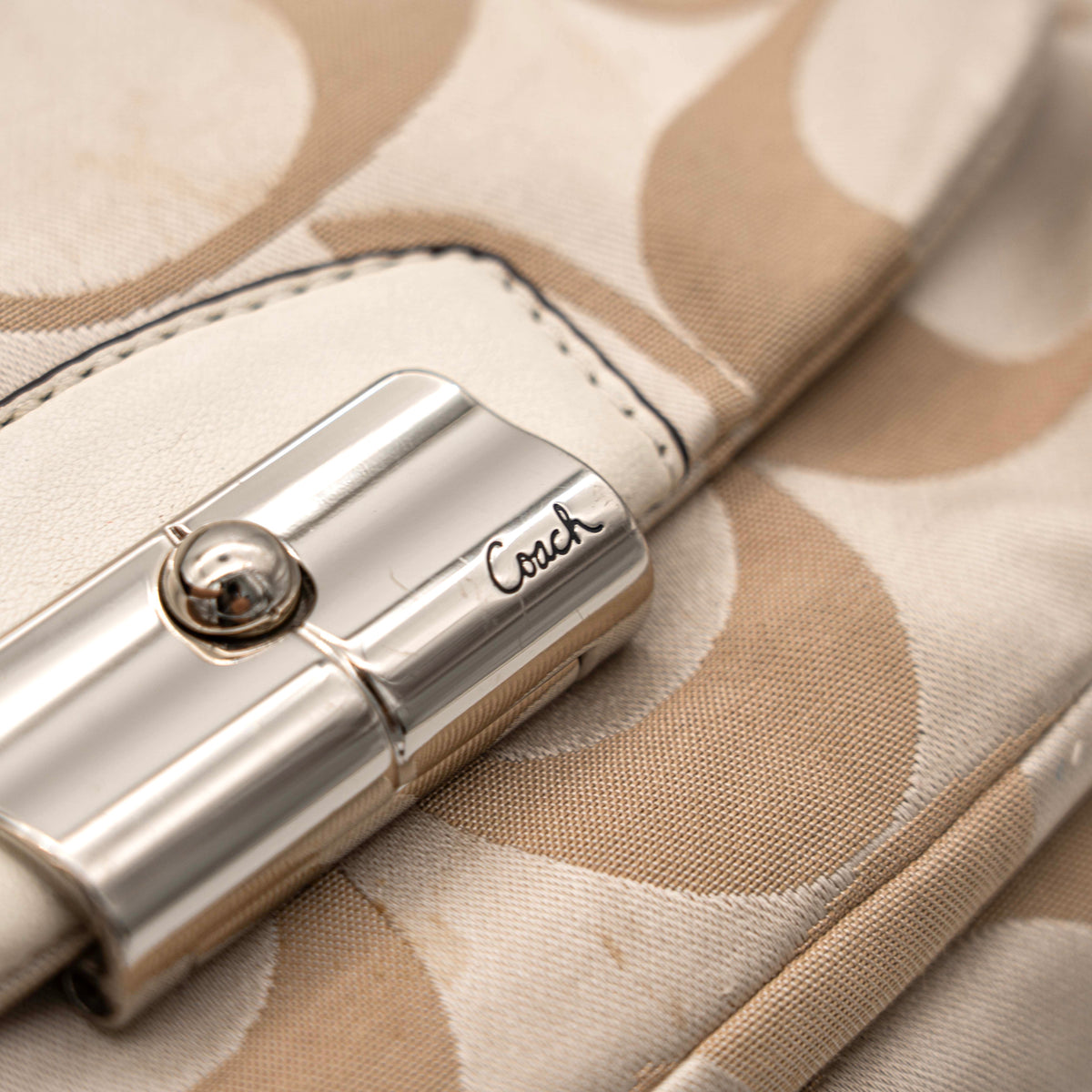 Coach Signature Kristin Satchel handbag in beige and cream jacquard with leather trim and detachable strap, displayed against a white background.