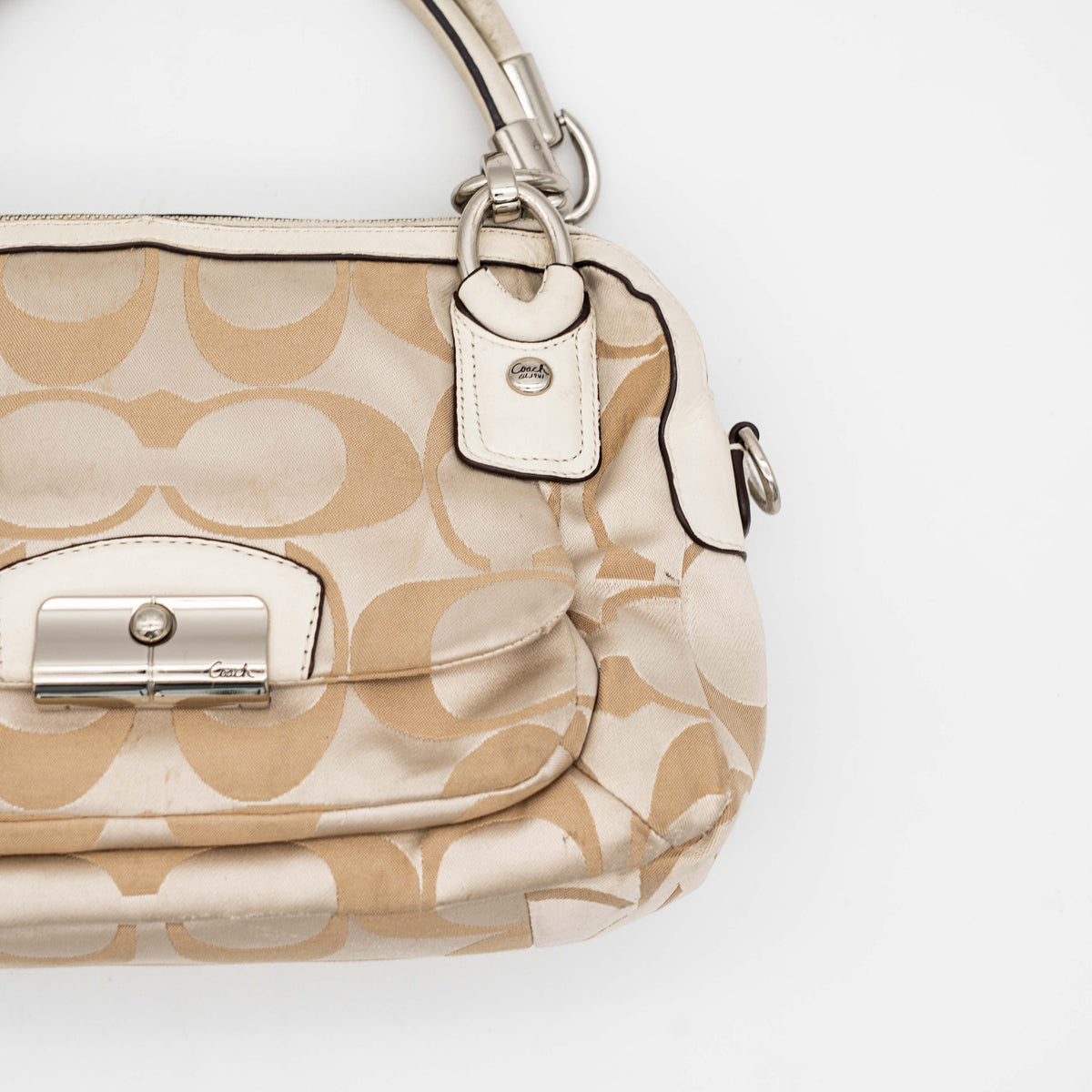 Coach Signature Kristin Satchel handbag in beige and cream jacquard with leather trim and detachable strap, displayed against a white background.