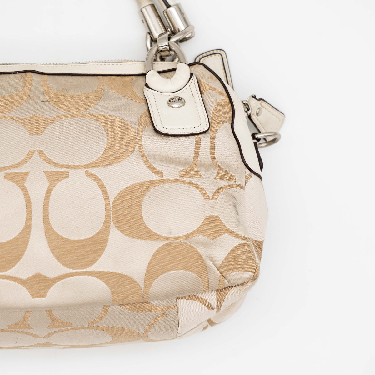 Coach Signature Kristin Satchel handbag in beige and cream jacquard with leather trim and detachable strap, displayed against a white background.