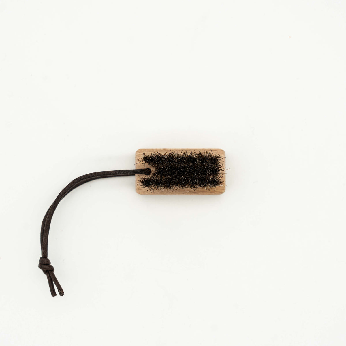 Coach horsehair leather care brush with wood handle and brown bristles, featuring a Coach logo and leather cord loop.