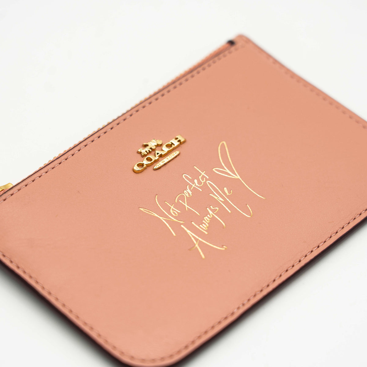 Coach x Selena Gomez colorblock zip card case in pink, burgundy, and black leather with gold hardware and script detail.