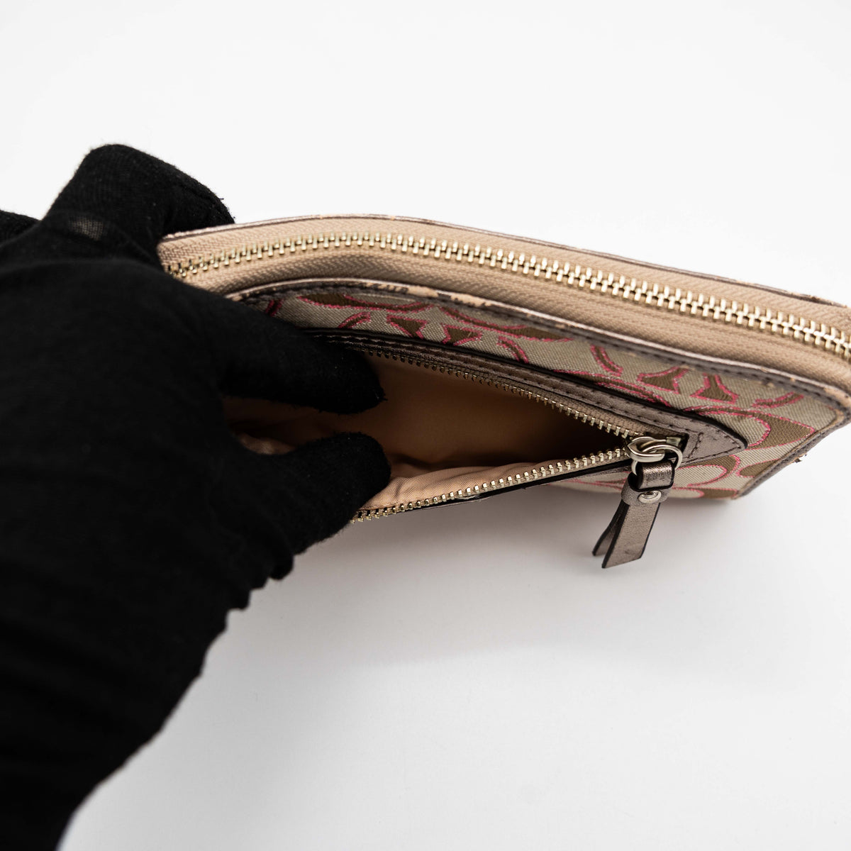 Coach Signature Daisy Accordion Zip Wallet in beige and pink canvas with zip pocket and metallic trim, photographed on a white background.