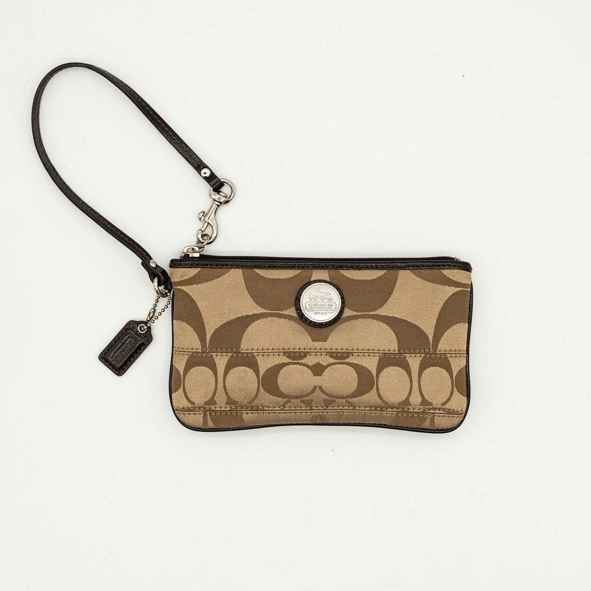 Coach brown monogram wristlet with silver badge and detachable leather strap, photographed on a white background.