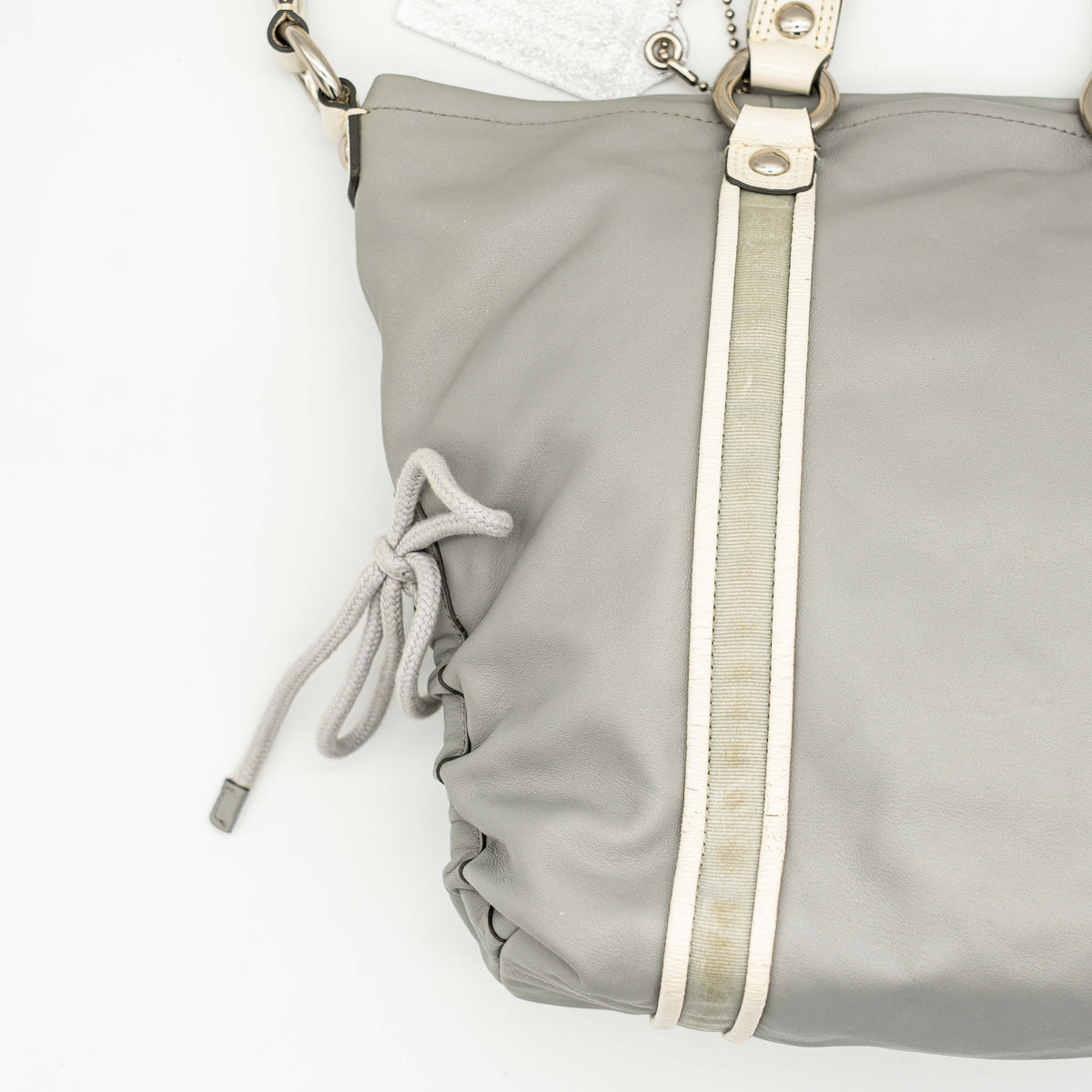 Coach Poppy Spotlight grey shoulder bag with double top handles, white trim, and detachable webbing strap, displayed on a white background.