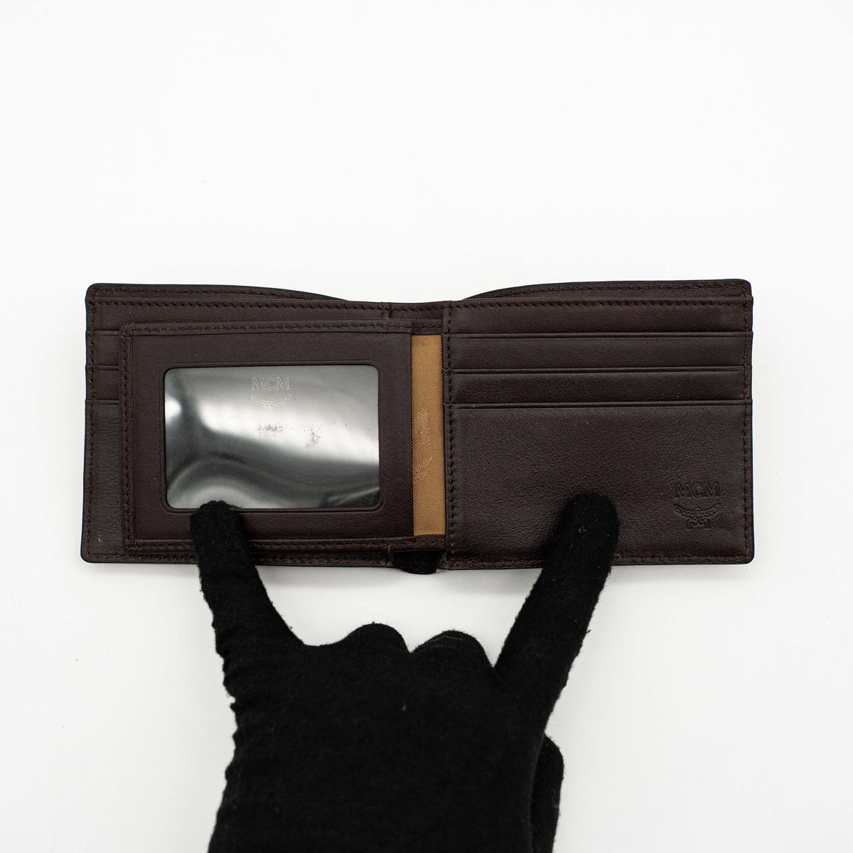 MCM dark brown leather bifold wallet with embossed Visetos monogram pattern shown against a white background.