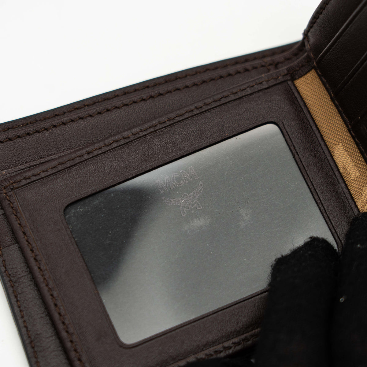 MCM dark brown leather bifold wallet with embossed Visetos monogram pattern shown against a white background.
