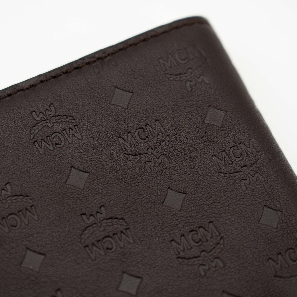 MCM dark brown leather bifold wallet with embossed Visetos monogram pattern shown against a white background.