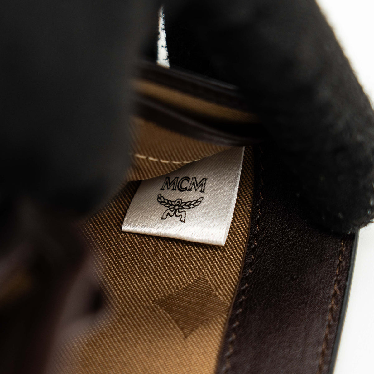 MCM dark brown leather bifold wallet with embossed Visetos monogram pattern shown against a white background.