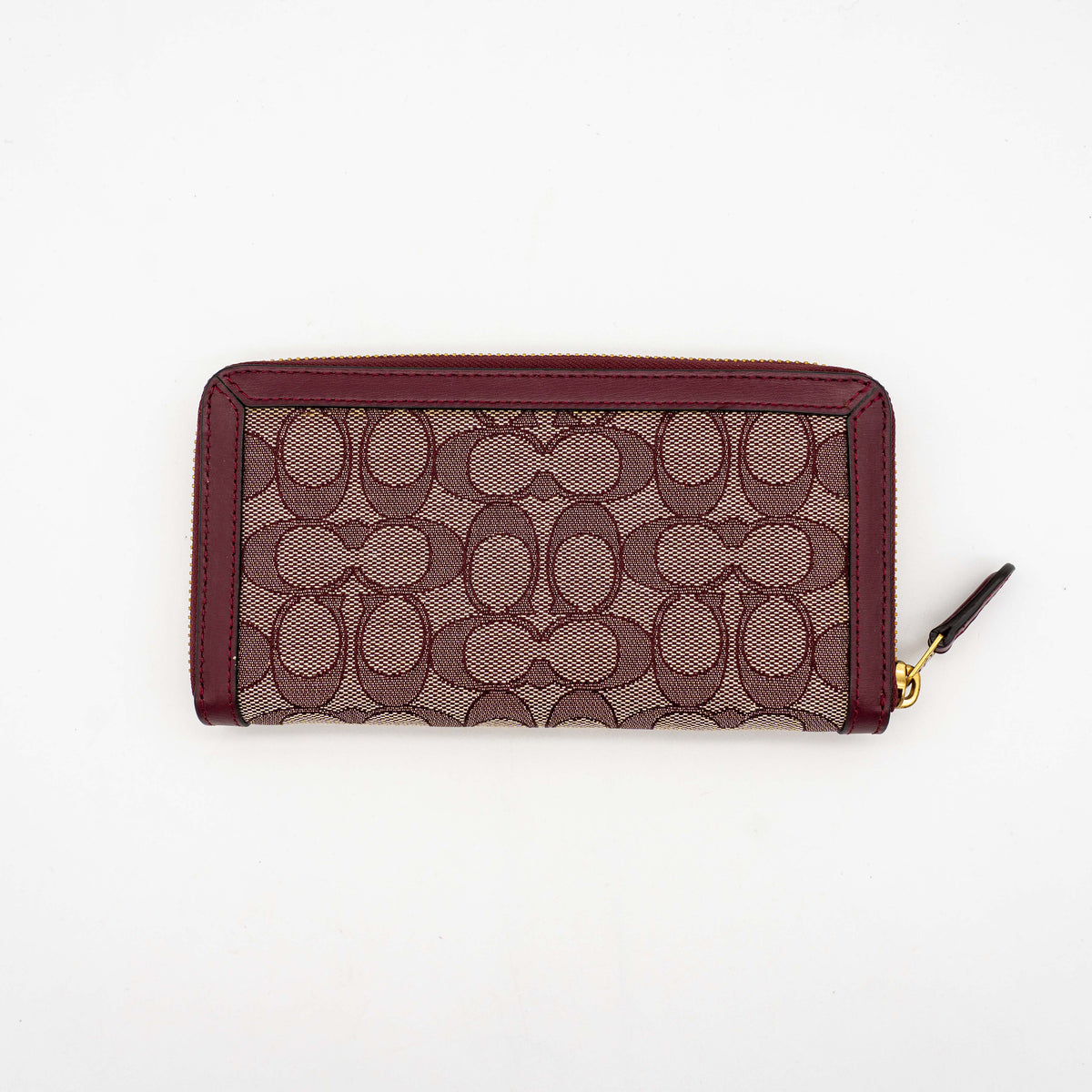 Coach Signature Accordion Zip Wallet in burgundy monogram canvas with leather trim and gold zip, photographed against a clean white background.