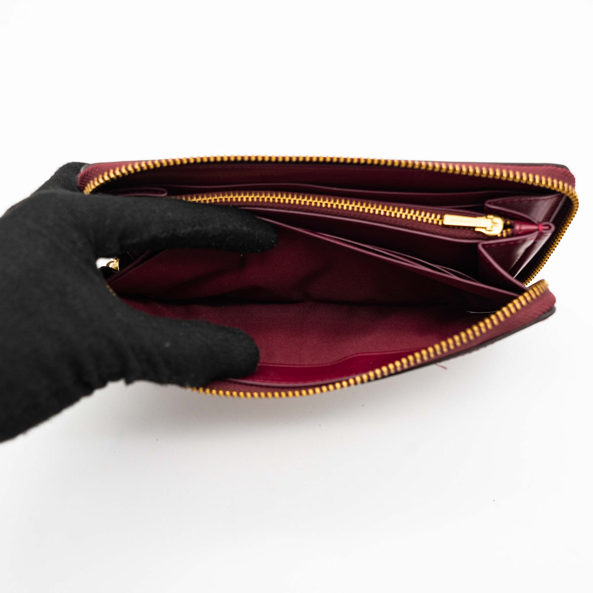 Coach Signature Accordion Zip Wallet in burgundy monogram canvas with leather trim and gold zip, photographed against a clean white background.