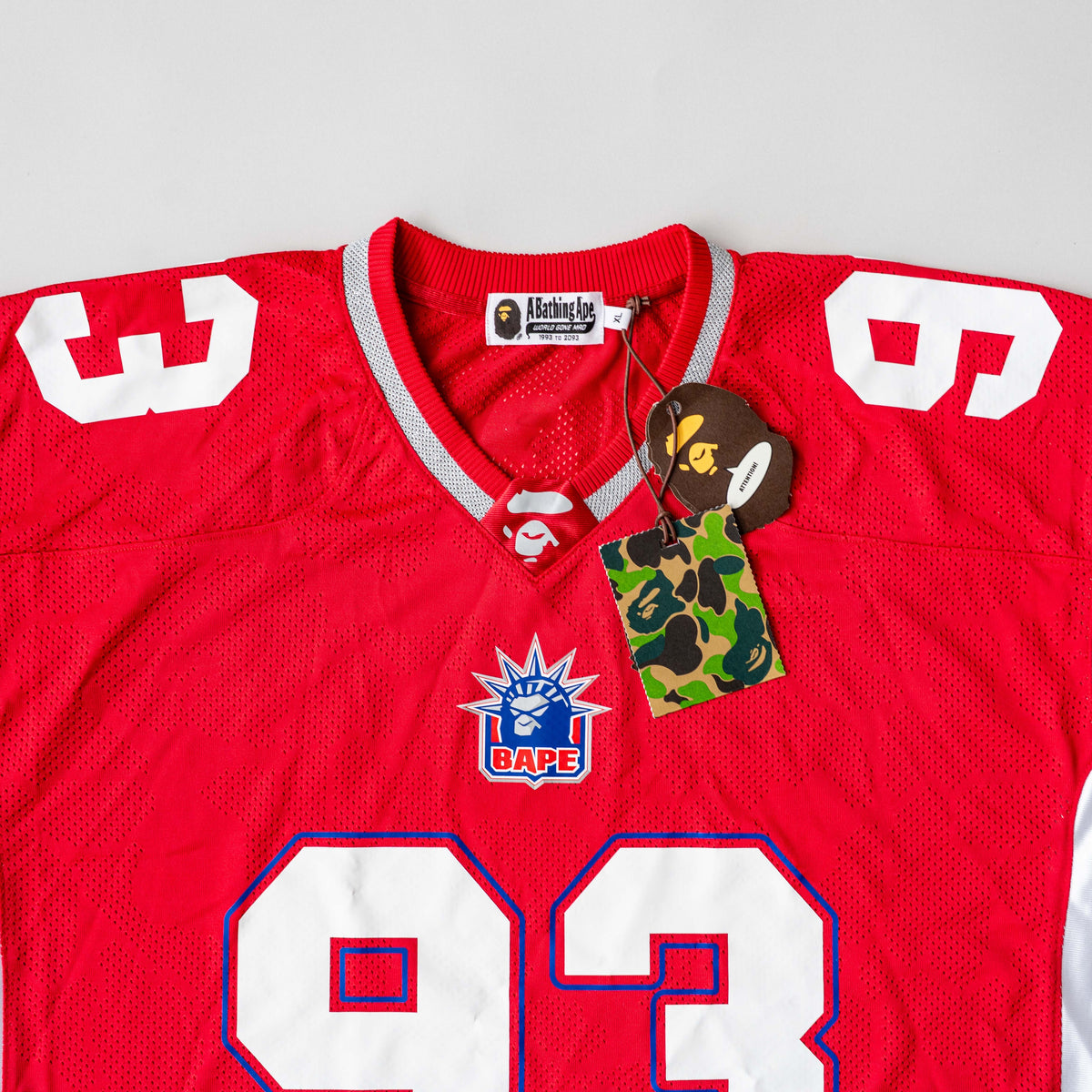 Front view of BAPE Solid Camo Jacquard Mesh Cropped Fit Football Jersey in red and white with bold '93' print and original tags.