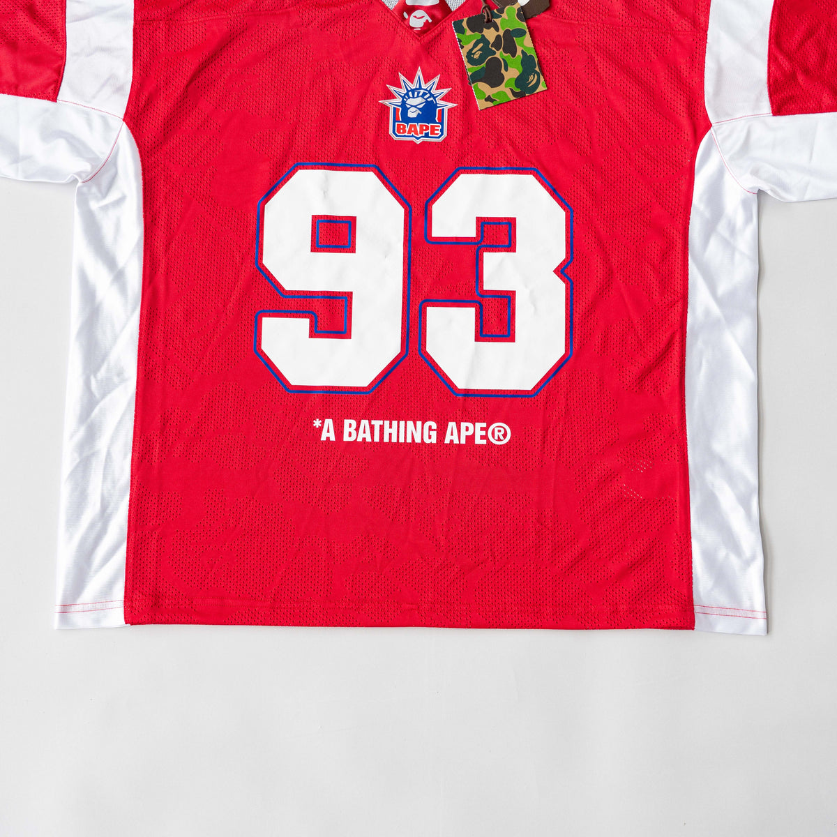 Front view of BAPE Solid Camo Jacquard Mesh Cropped Fit Football Jersey in red and white with bold '93' print and original tags.