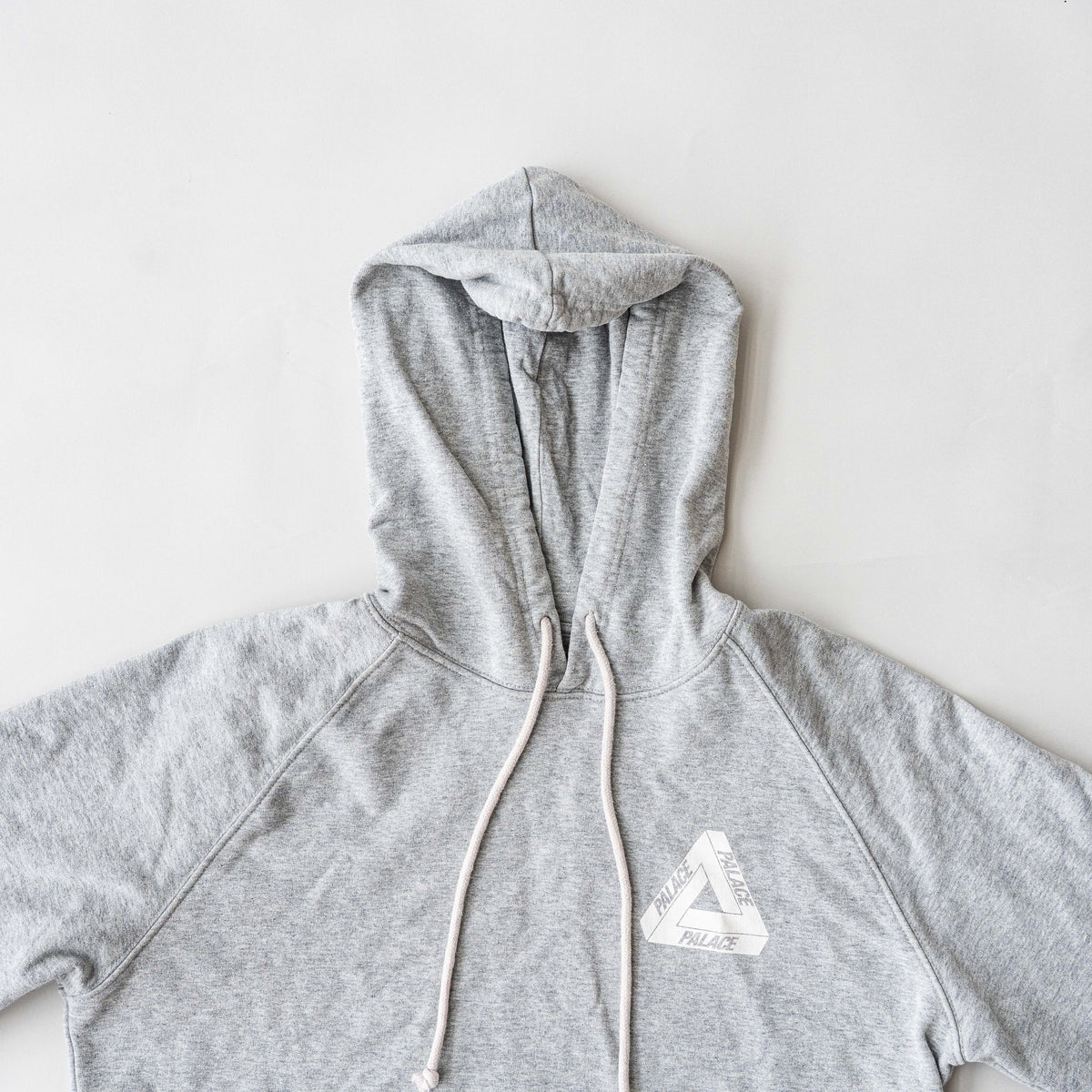 Palace grey pullover hoodie with tropical Tri-Ferg back graphic and white chest logo, laid flat on a neutral background.