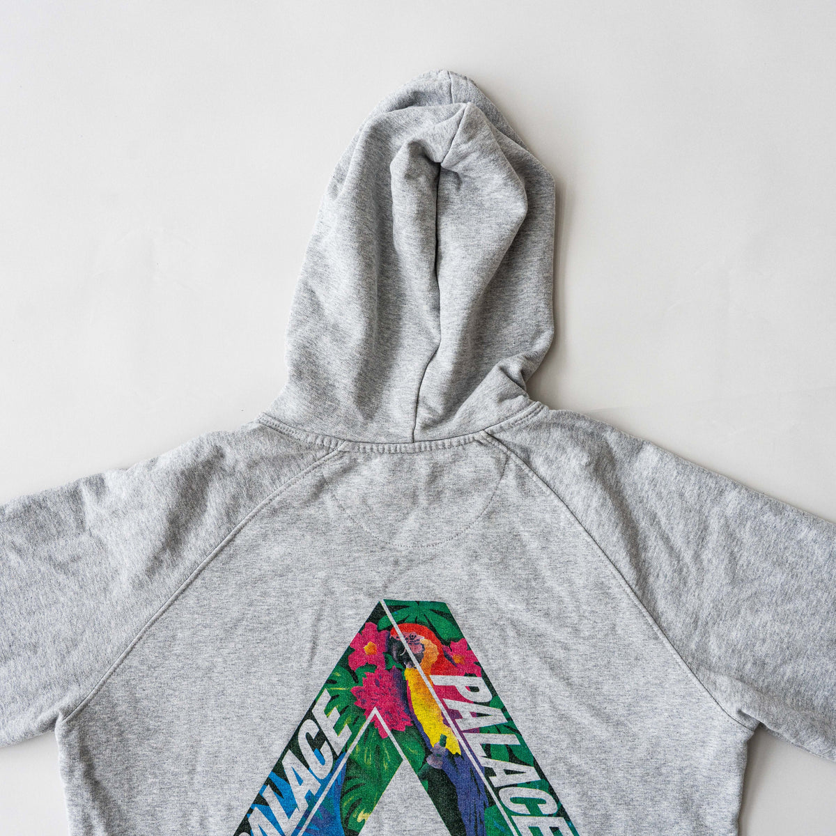 Palace grey pullover hoodie with tropical Tri-Ferg back graphic and white chest logo, laid flat on a neutral background.