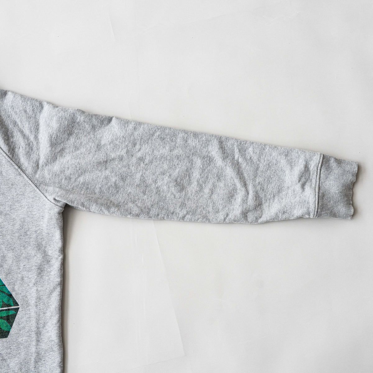 Palace grey pullover hoodie with tropical Tri-Ferg back graphic and white chest logo, laid flat on a neutral background.